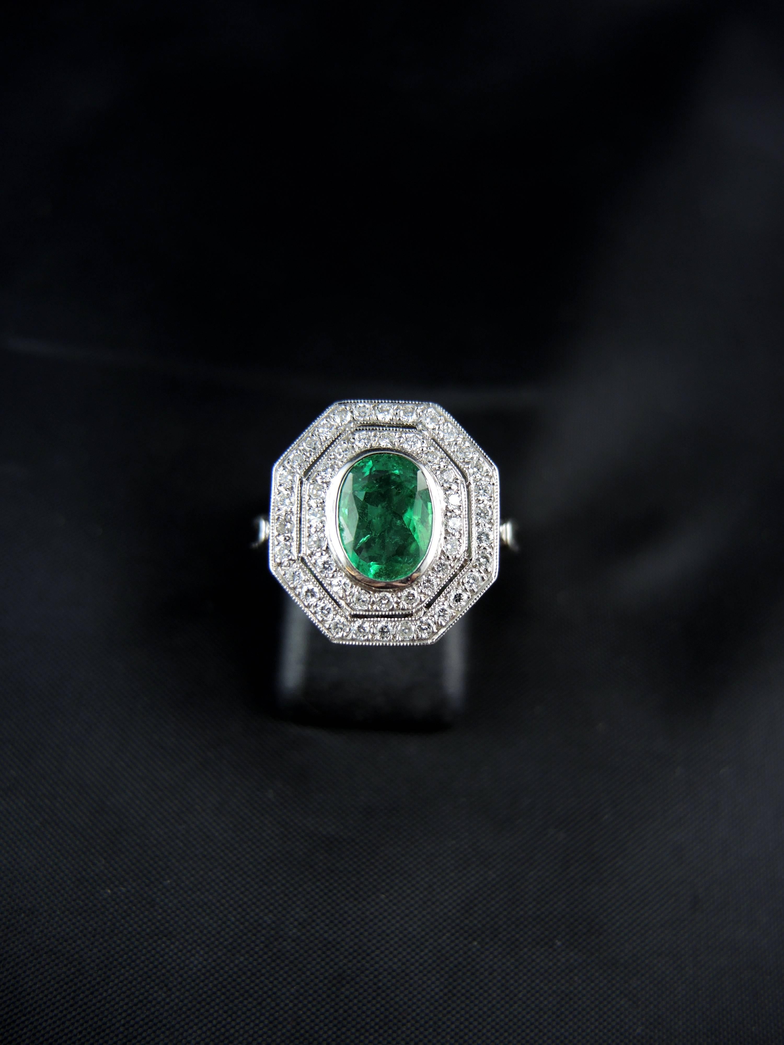 18 Kt white gold Art Deco style cluster ring (quality mark: head of eagle) set with a central oval emerald, weighting 1.24 Ct, surrounded with modern and single brilliant cut diamonds, which total weight is estimated around 0.37 Ct.

Recent French