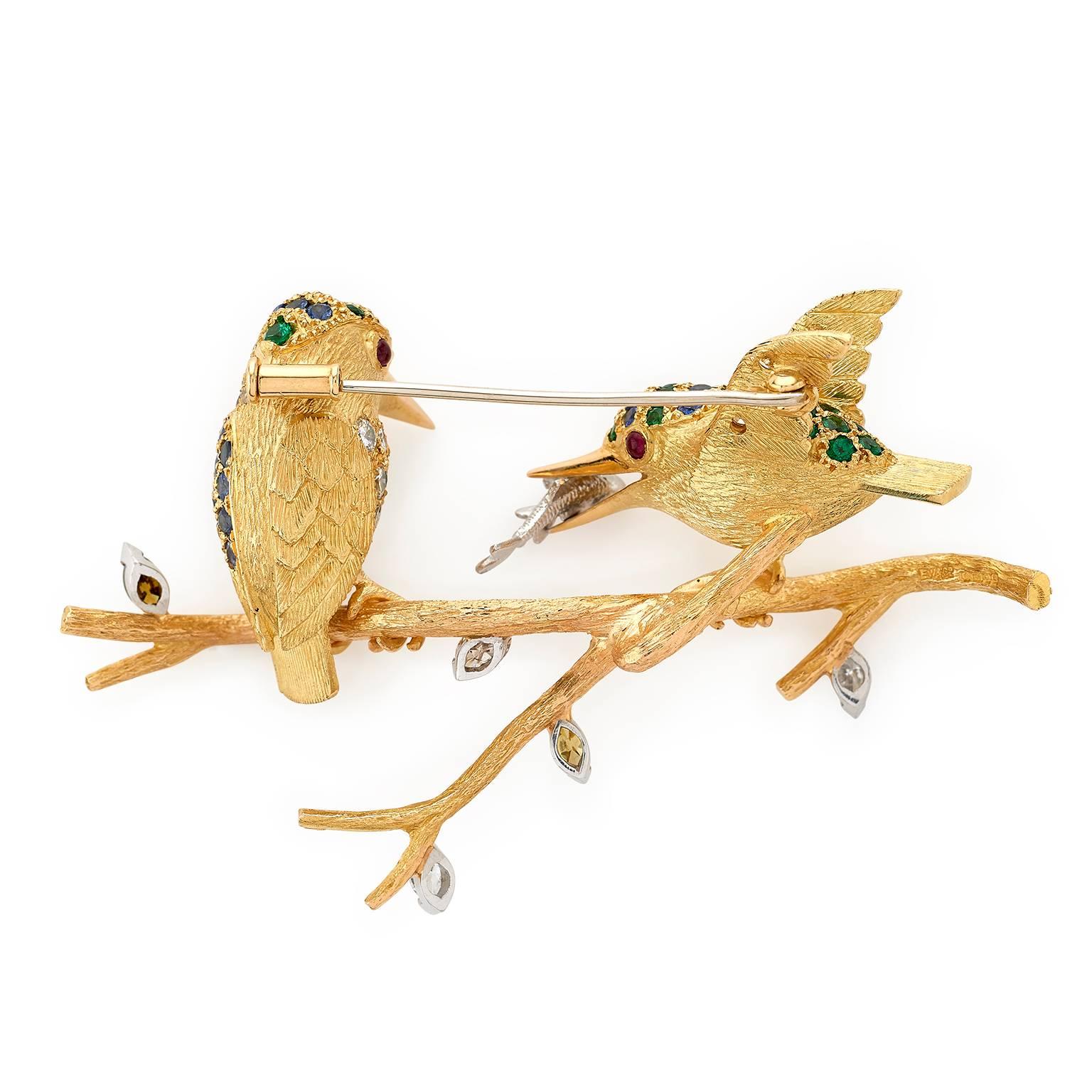 Two gem-set kingfishers brooch hand-carved in 18 carat yellow gold, one with 18 carat white gold fish in its mouth. The birds are set with 1.29 carats blue sapphires, 4.25 carats diamonds, 1.21 carats tsavorite garnets, ruby eyes and perched on 18