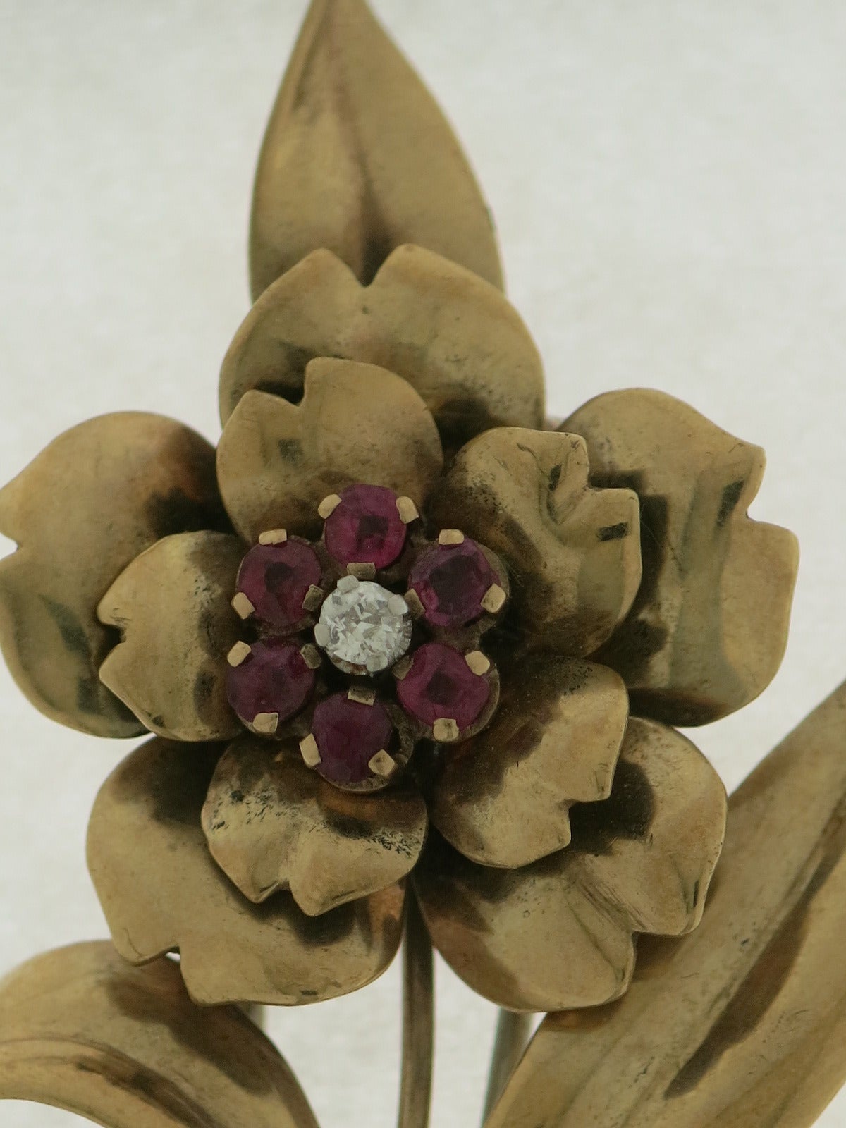 An elegant brooch flower-shaped in 18 kt yellow gold, diamonds and rubies