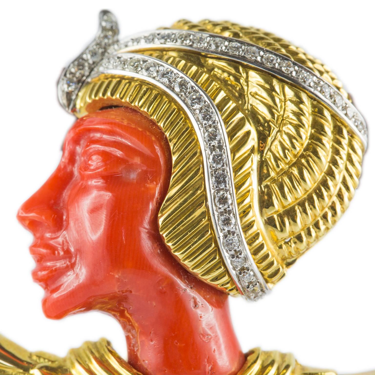 This egyptian revival style 18KT yellow gold brooch can also be worn as a pendant. Embellished by brilliant cut diamonds, the profile and the bead are in 9 ct. coral.