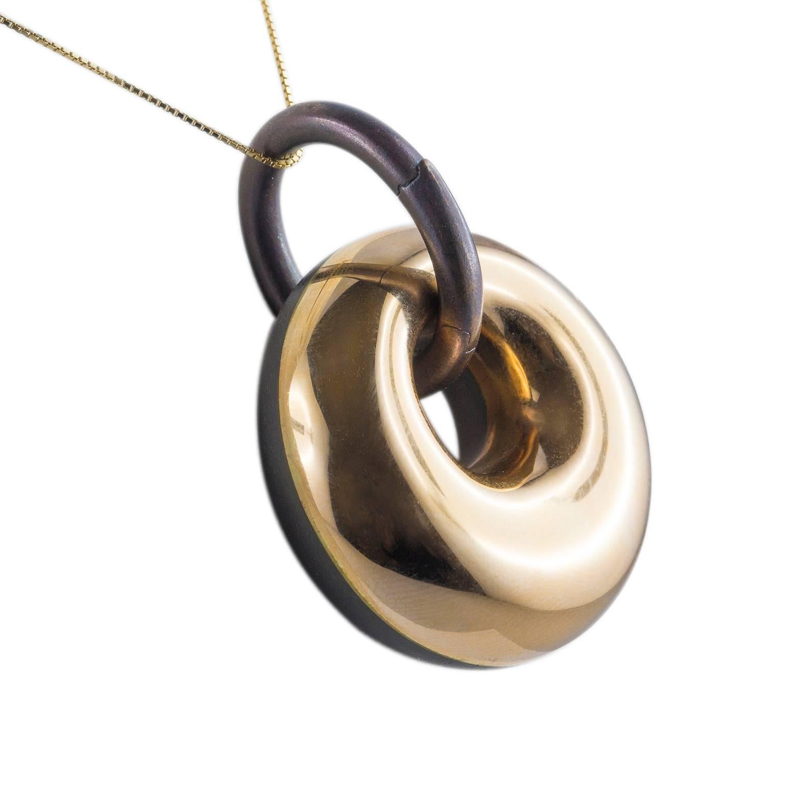 Modern pendant from the essential line in 18KT yellow gold and bronze. On the bronze side a small spot of light with a 0,02 ct brilliant cut diamond.