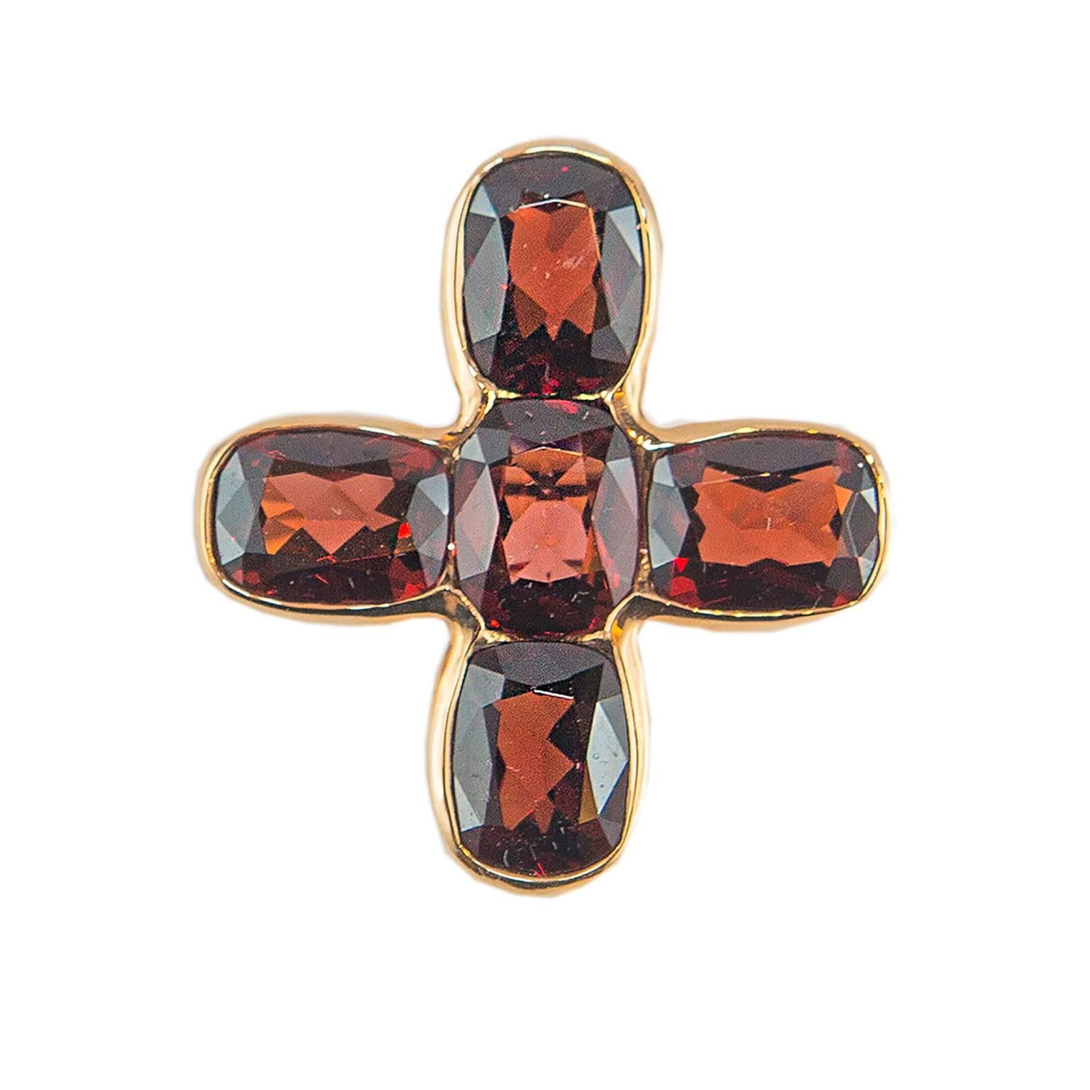 An 18KT rose gold ring with a modern and bright cross with four garnets.