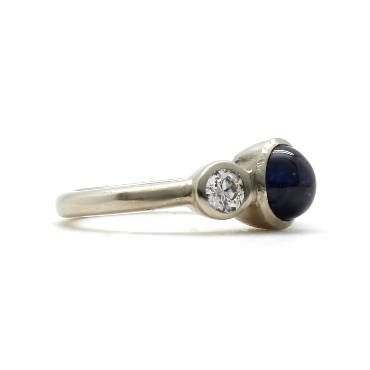 This one-of-a-kind 14k white gold ring features an antique natural 1.92 carat blue sapphire cabochon with no indications of heat treatment. It is accented by two Old European Cut diamonds with a total carat weight of 0.45, H-I color and SI1-I2