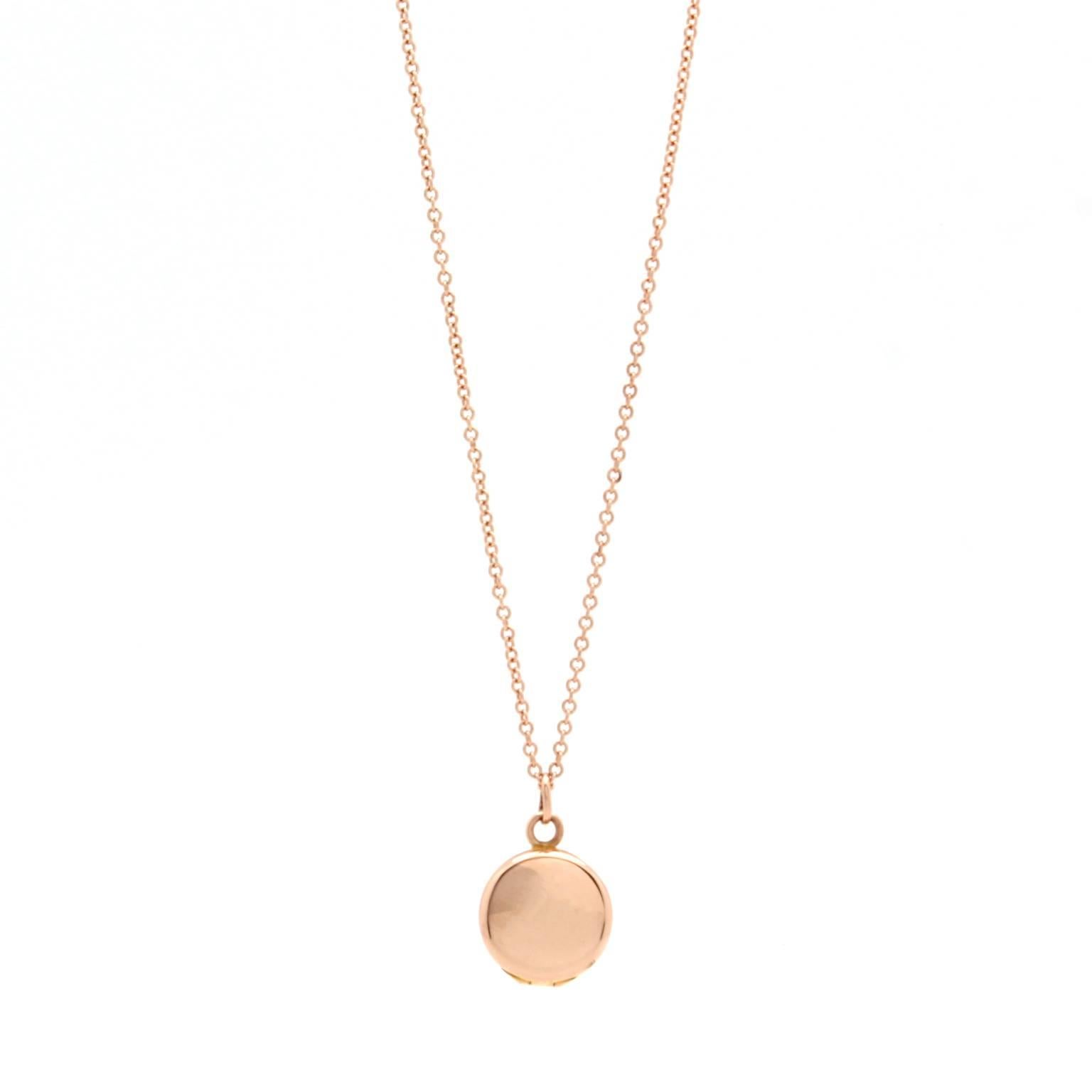 This vintage locket features hand engraving on its front and a polished smooth metal back. It is made of 14k rose gold and hangs from a new 14k rose gold 16″ chain. The locket measures 9mm in diameter.

