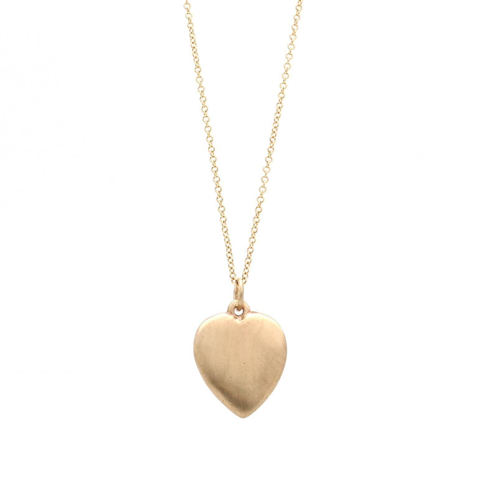 This 14k yellow gold heart pendant features a raised wishbone motif. The heart is rounded on the front and back and the metal has a satin finish. The pendant is solid (not hollow) and is made of reclaimed gold. The heart measures 13mm by 15mm and