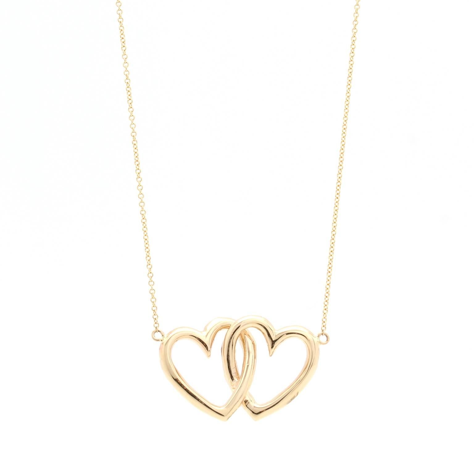 This 14k yellow gold necklace features two ornately carved overlapping hearts. 
The pendant measures 28mm by 20mm and hangs from a 17″ chain. The hearts are solid metal (not hollow) and feature a polished finish. 

