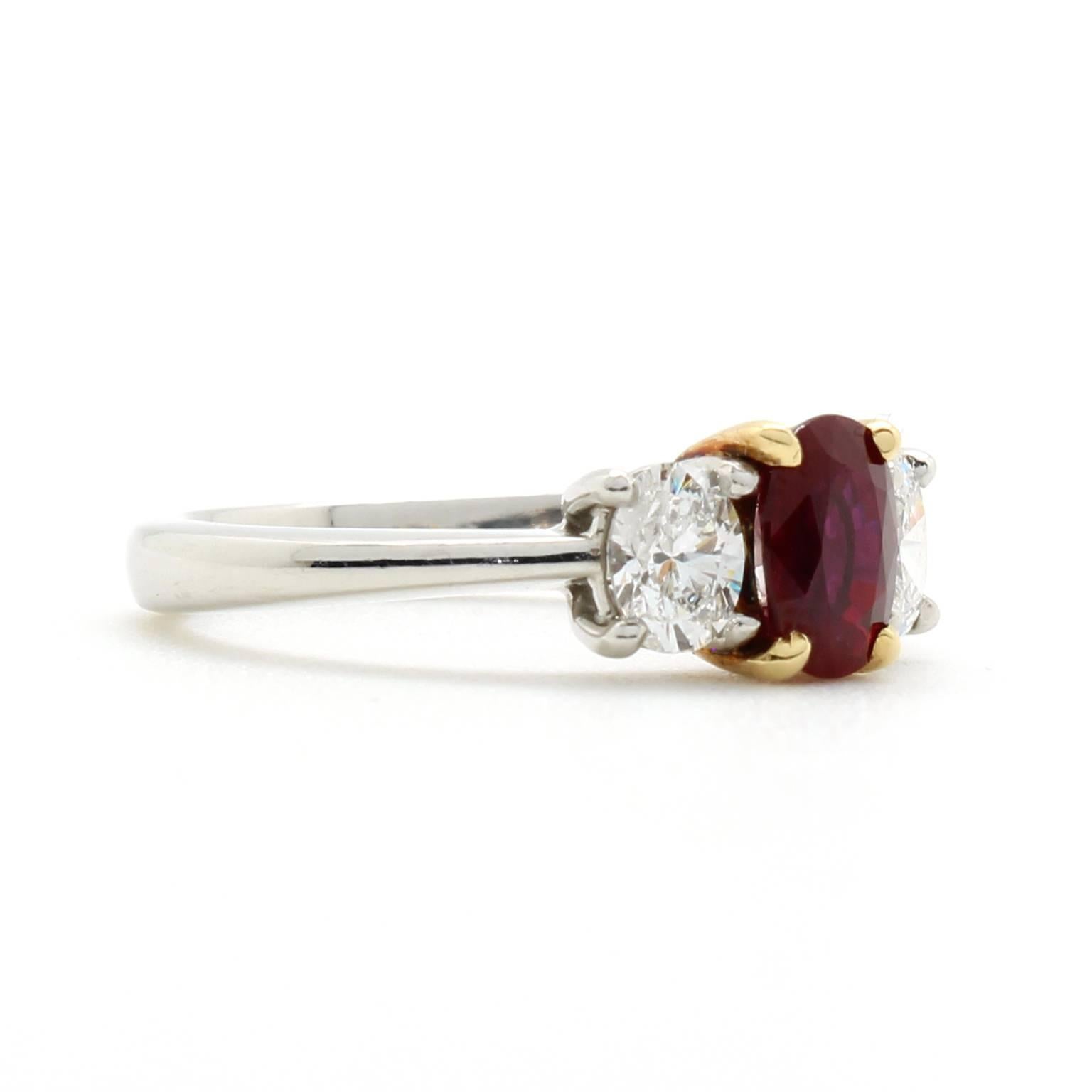 This two-tone vintage ring features a natural ruby set in 18k yellow gold prongs. The weight of the ruby is 1.08 carats and measures 6.8mm by 4.8mm in dimension. Two oval diamonds accent the ruby and have a total weight of 0.62 carats, F color and