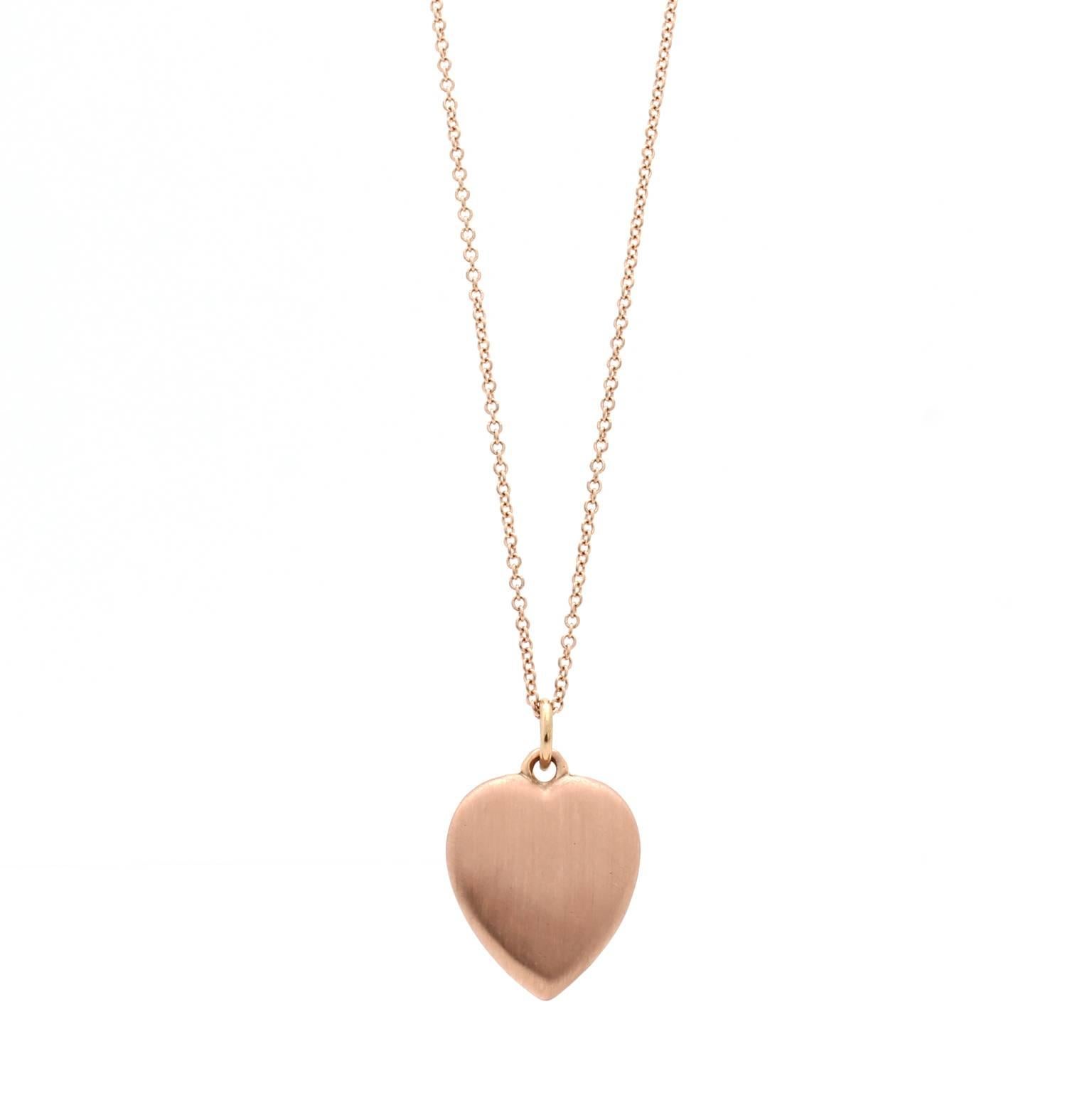 This 18k rose gold heart pendant features a raised wishbone motif. The heart is rounded on the front and back and the metal has a satin finish. The pendant is solid (not hollow) and is made of reclaimed gold. The heart measures 13mm by 15mm and