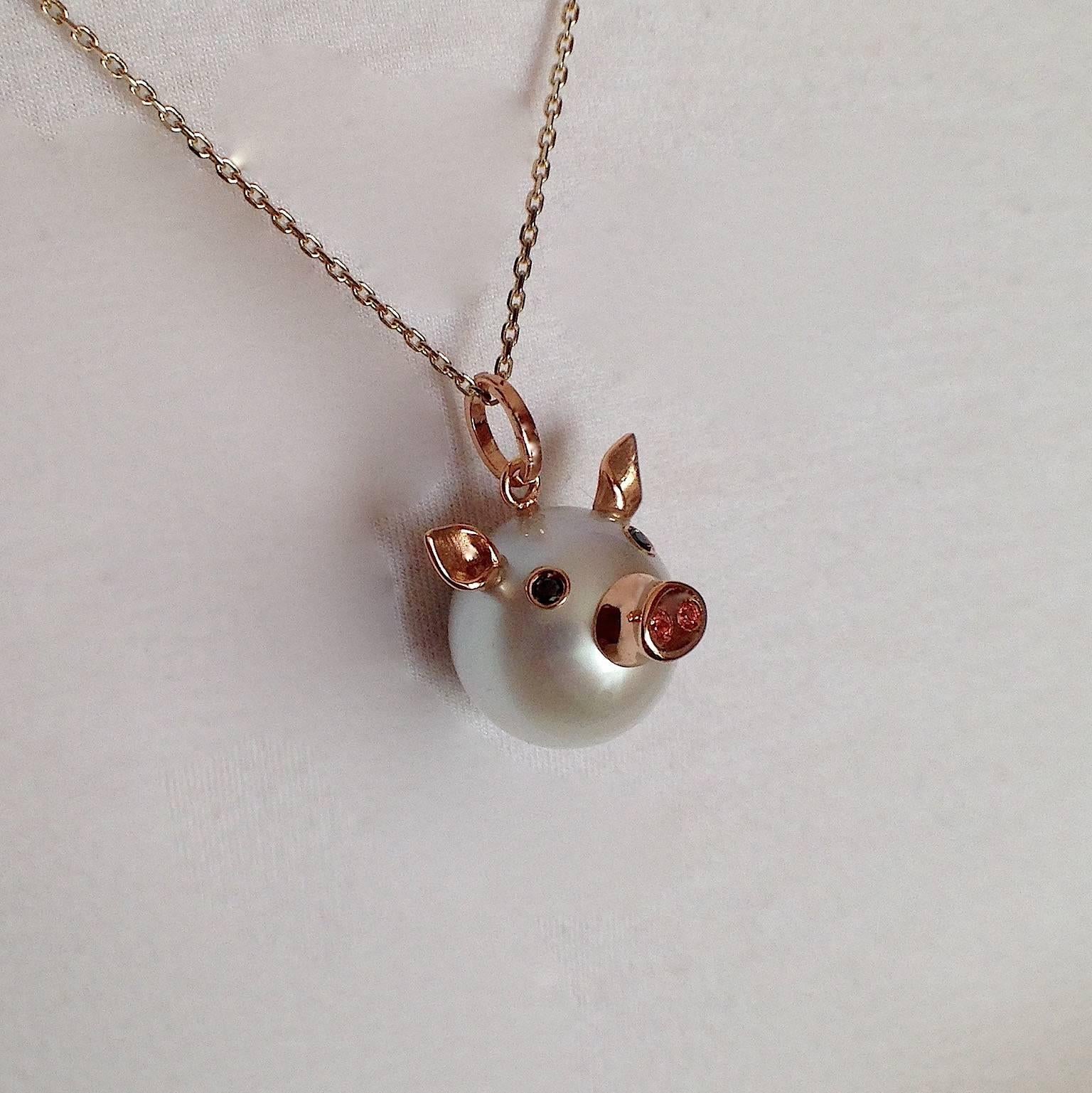 This nice pendant is made with a button Australian pearl. 
It has two ears, two eyes with black diamonds.  
In the holes of its nose there are two orange sapphires encrusted, in total ct 0.03.
All the particulars made in red gold.
The diamonds are