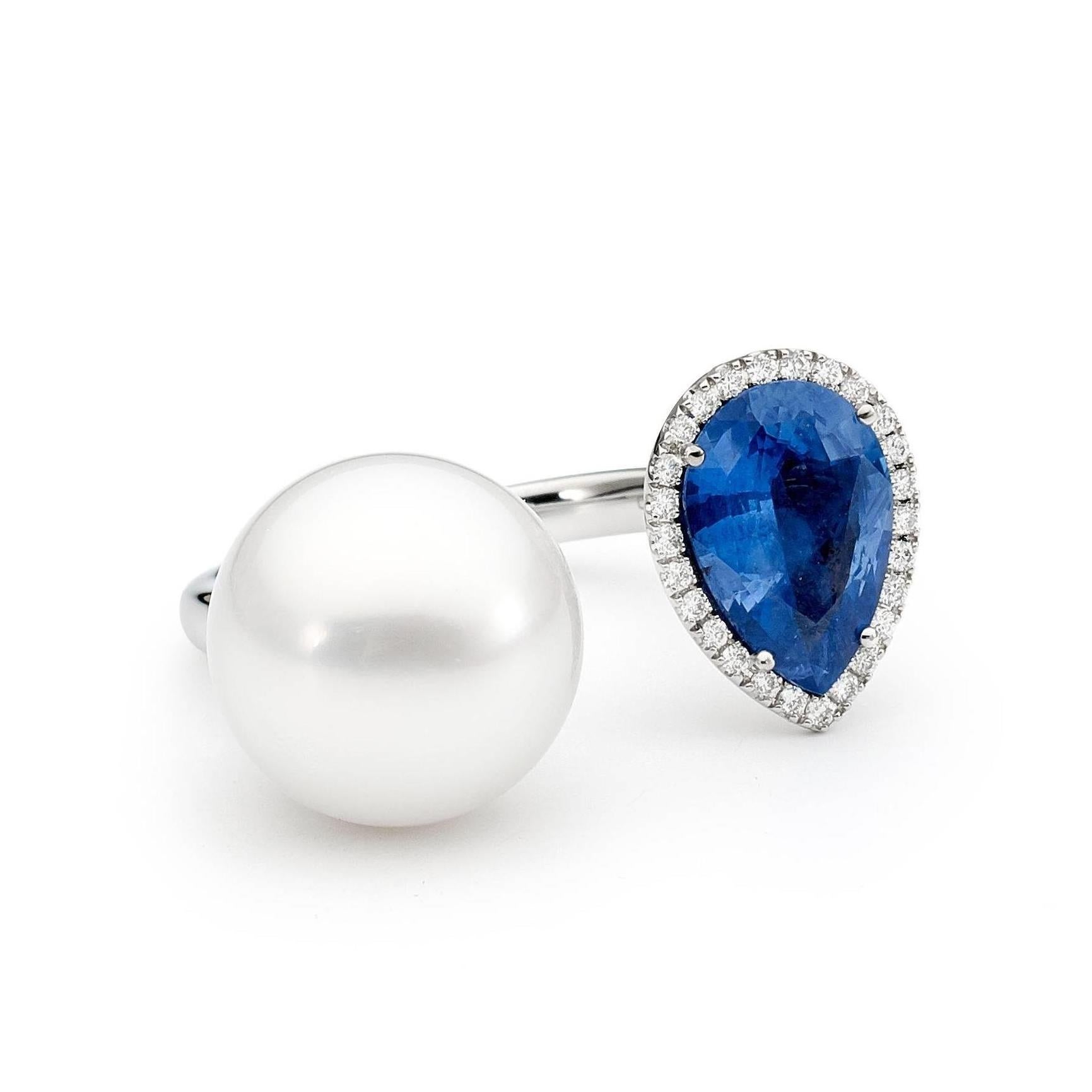 A timeless yet modern Open design Ring set with a stunning 2.32 ct Pear Shaped Blue Sapphire, encased by a halo of 26 fine white diamonds (weighing 0.13ct color H / SI1) and accompanied by a gorgeous 12mm White South Sea Pearl set into 18ct white