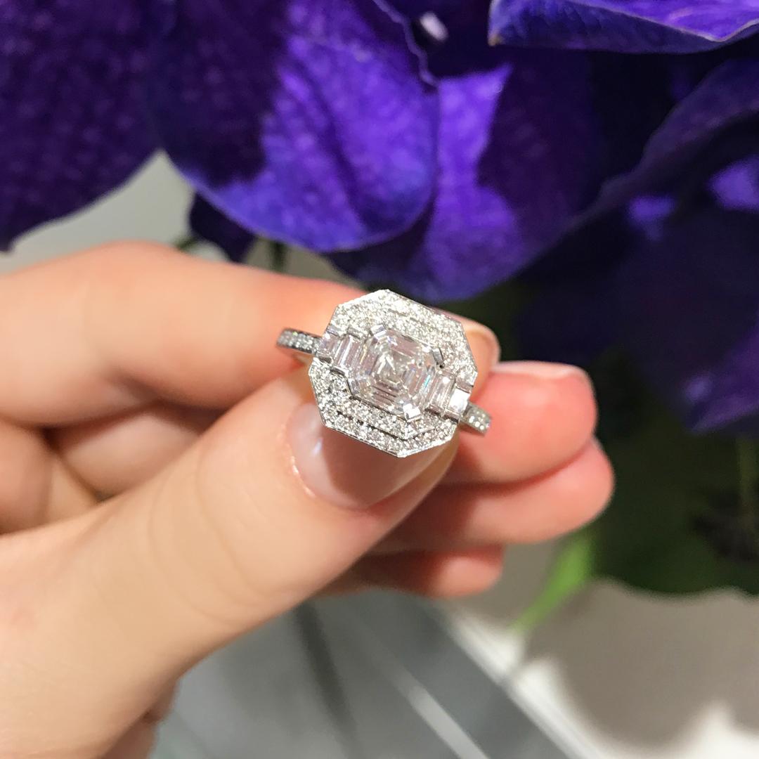 This stunning Matthew Ely engagement ring features a 1.31ct Asscher Cut Diamond (color F clarity SI1) encased between two halos of white Diamonds and finished with a Divine micro pave Diamond set platinum band (total weight 0.47ct color FG clarity