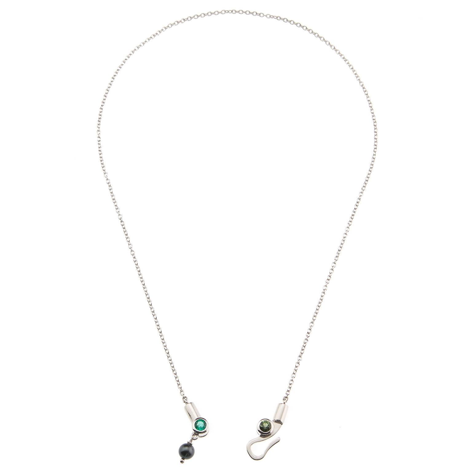 Micro pendant drop necklace in 18 karat white gold from the Microcosmos Series, is devised as a game, a construction or a sophisticated aerial mobile. Shapes attached to gold settings dangle lightly on the neck, their geometry pierced by emerald,