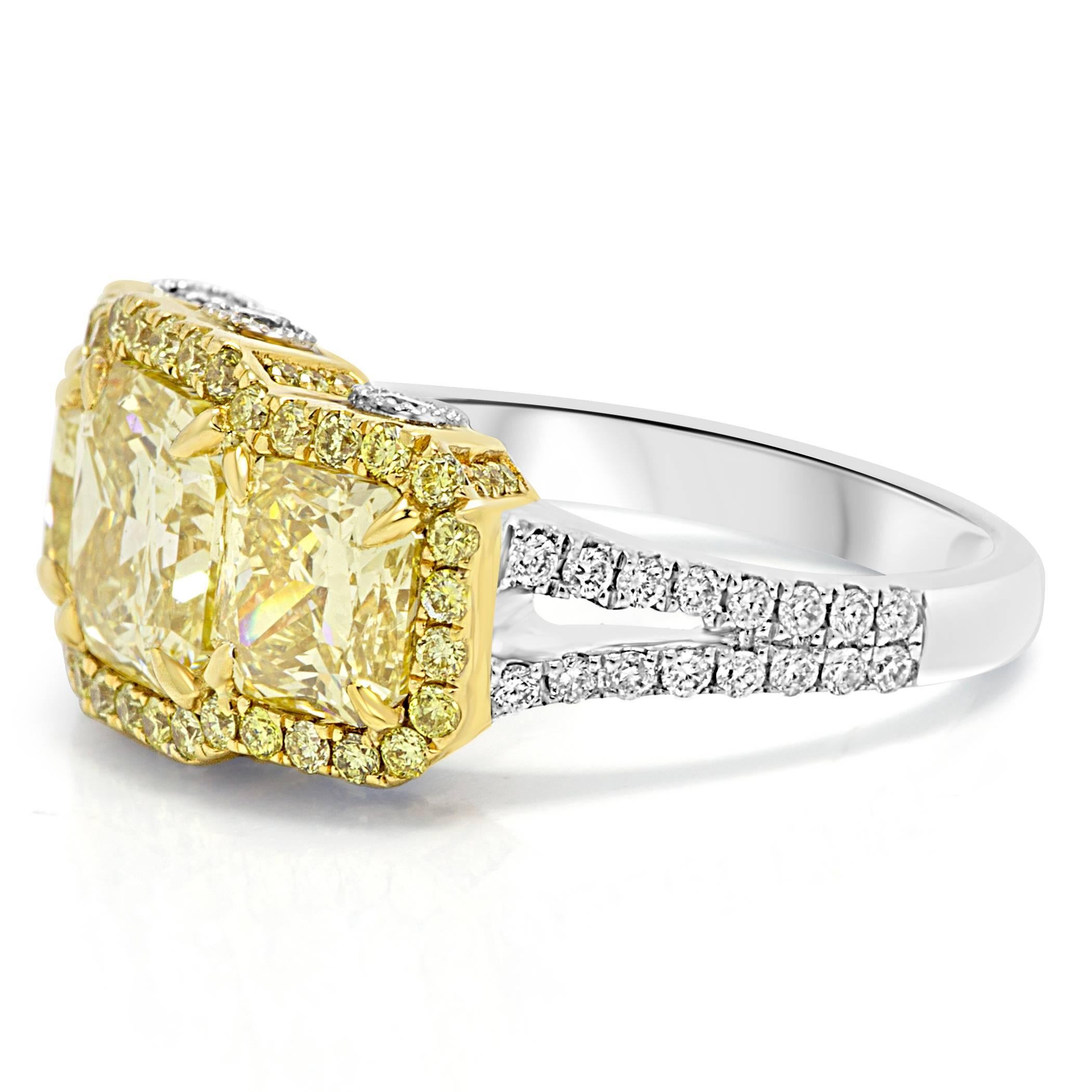 Gorgeous one of a kind 1 Natural Fancy Yellow Radiant cut Diamond 2.06 Carat Flanked by 2 Natural Fancy Yellow Diamond 2.14 Carat encircled in a single Halo of natural fancy yellow round Diamonds 0.44 Carat, with white diamond rounds on the shank