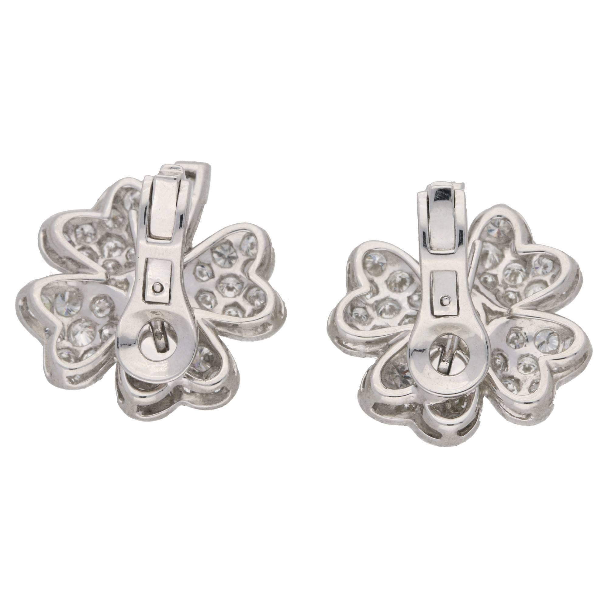 A lucky pair of vintage platinum and diamond four leaf clover earrings. Each earring has a transitional brilliant cut diamond centrally set in a mille grain collet, with four leaves of pave set round brilliant cut diamonds and a calibre cut channel