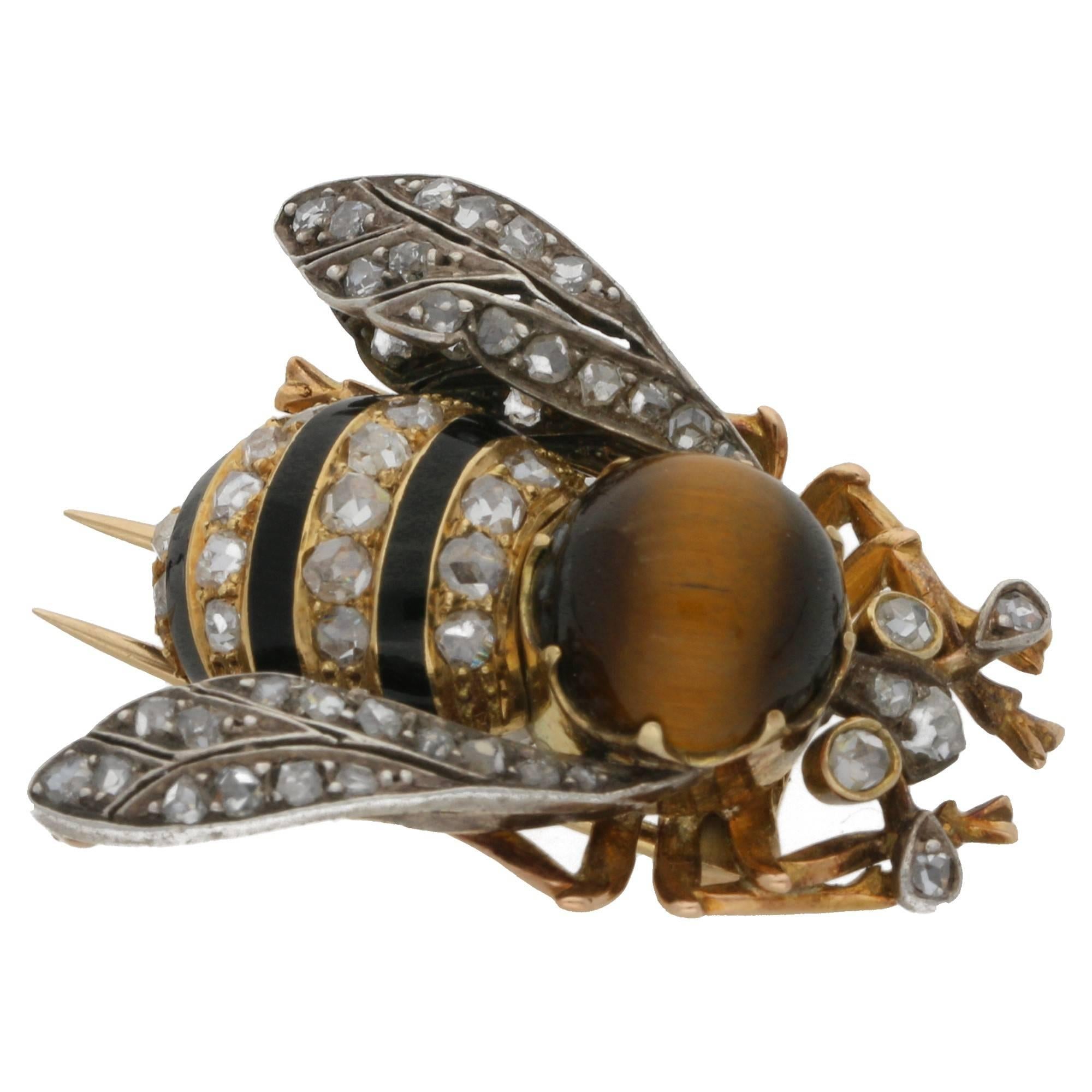 A striking Victorian tiger's eye, diamond and black enamel bee brooch set in silver on gold.The thorax is a cabochon tiger's eye quartz, the abdomen is covered with alternating bands of black enamel and french rose-cut diamonds, the pierced openwork