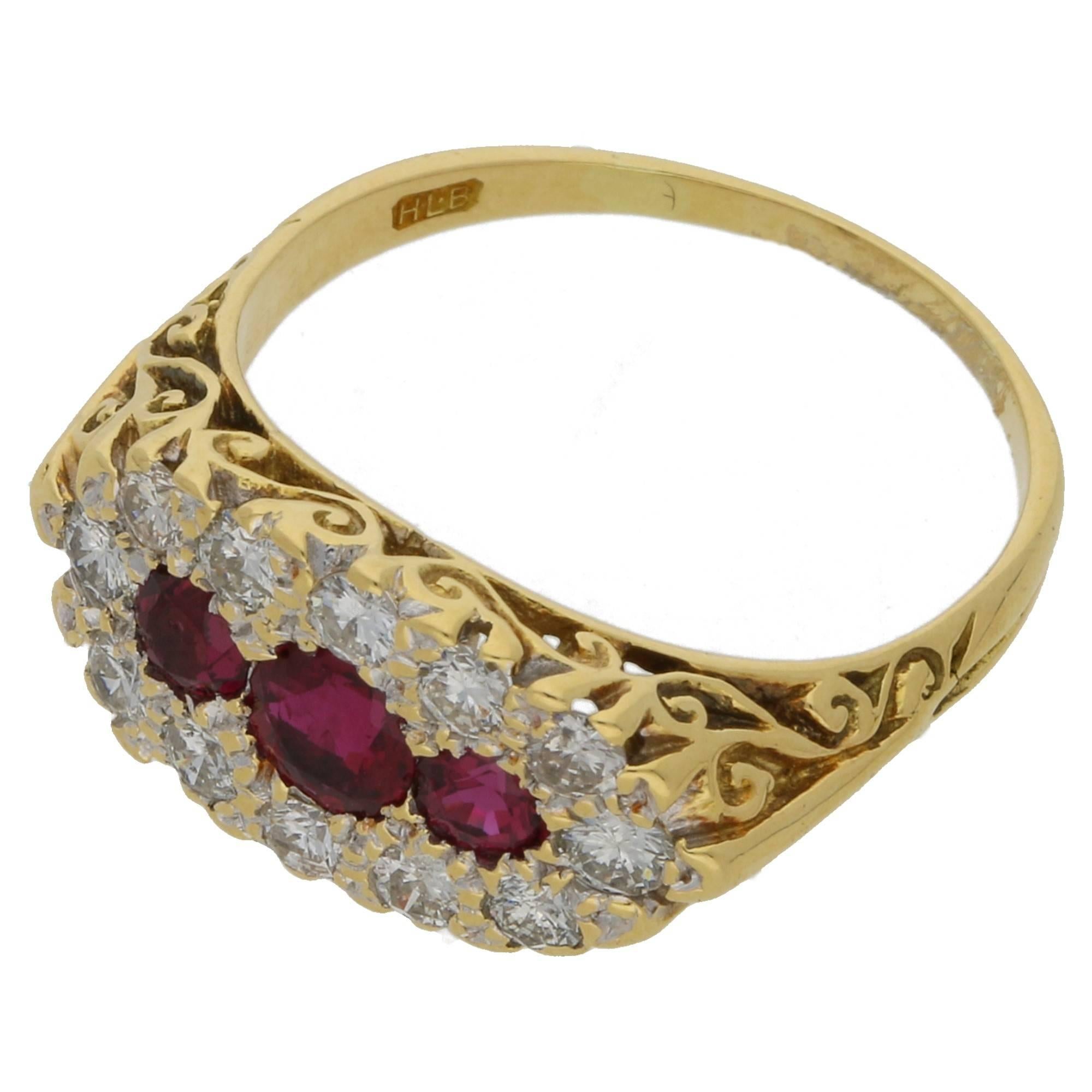 A Victorian style boat head ring set in 18ct yellow gold. With three round faceted rubies pave set centrally amidst a surround of round brilliant cut diamonds. The face leads to an ornate hand carved scroll work undercarriage and shoulders.