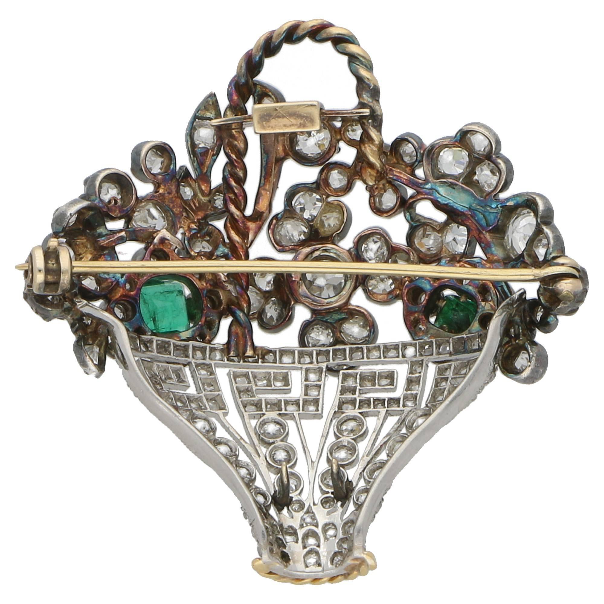 An antique diamond and emerald flower basket brooch set in silver on gold and platinum. The floral display is early Victorian and exhibits a pair of emerald cut emeralds amidst a diamond verdure of Old Mine cut diamonds set in silver on gold. 

The