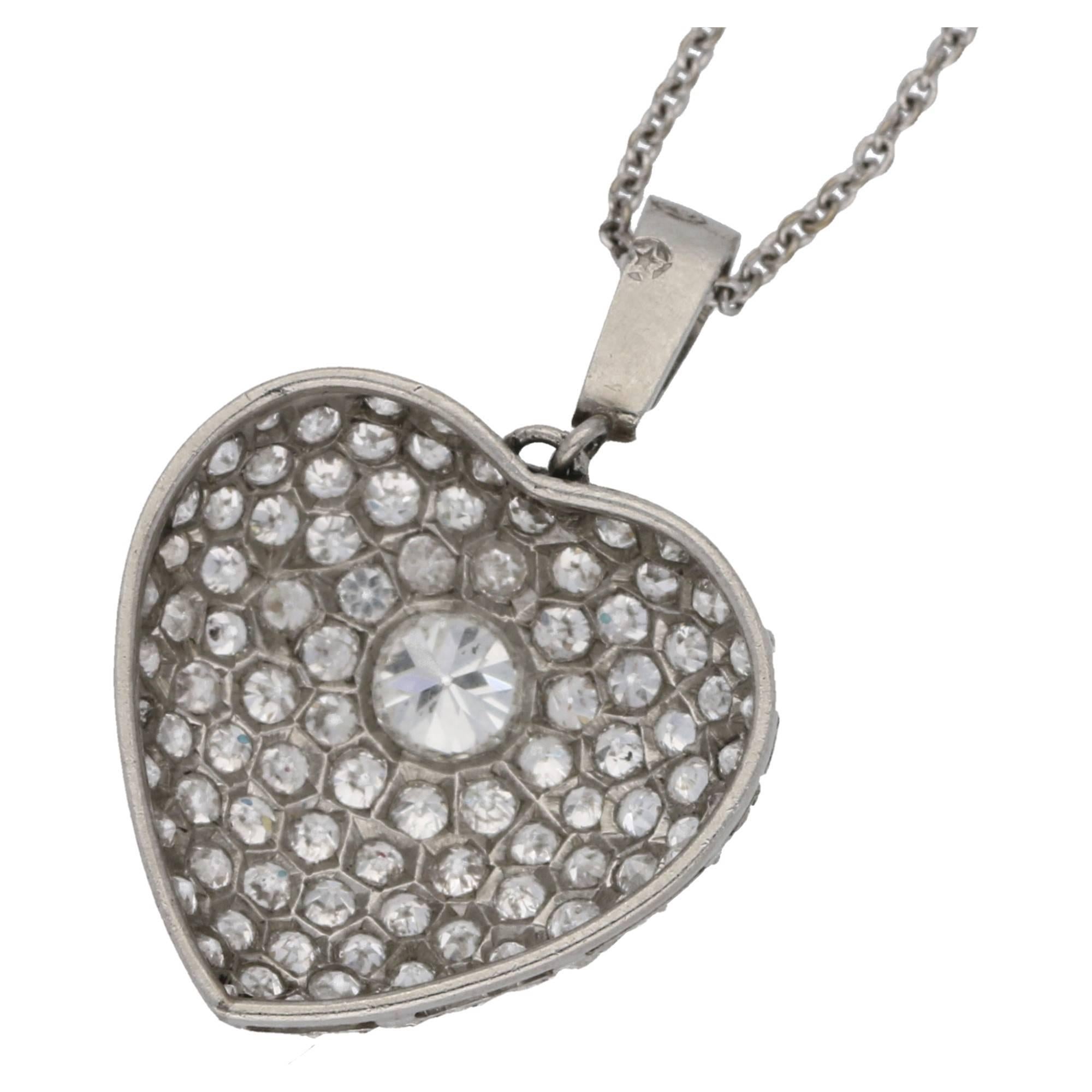 An exquisite diamond heart pendant set in platinum from the Edwardian era. The heart is set with an incredible assortment of old European cut diamonds pave set around a larger central diamond. The pendant is suspended on a diamond set bale with a