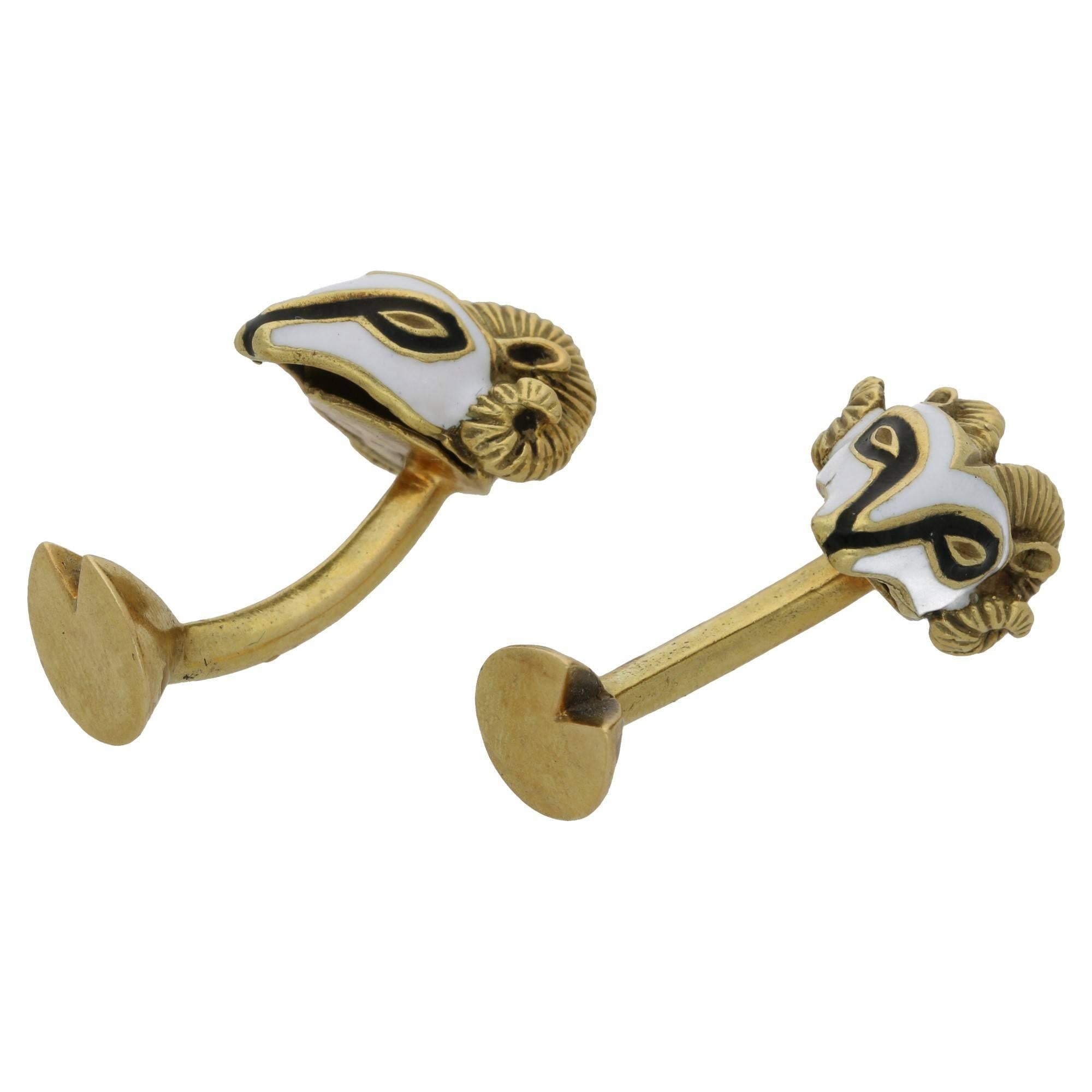 A fine pair of 18ct yellow gold and black and white enamel rams head cufflinks, embellished with a cloven hoof terminal the to solid barbell.