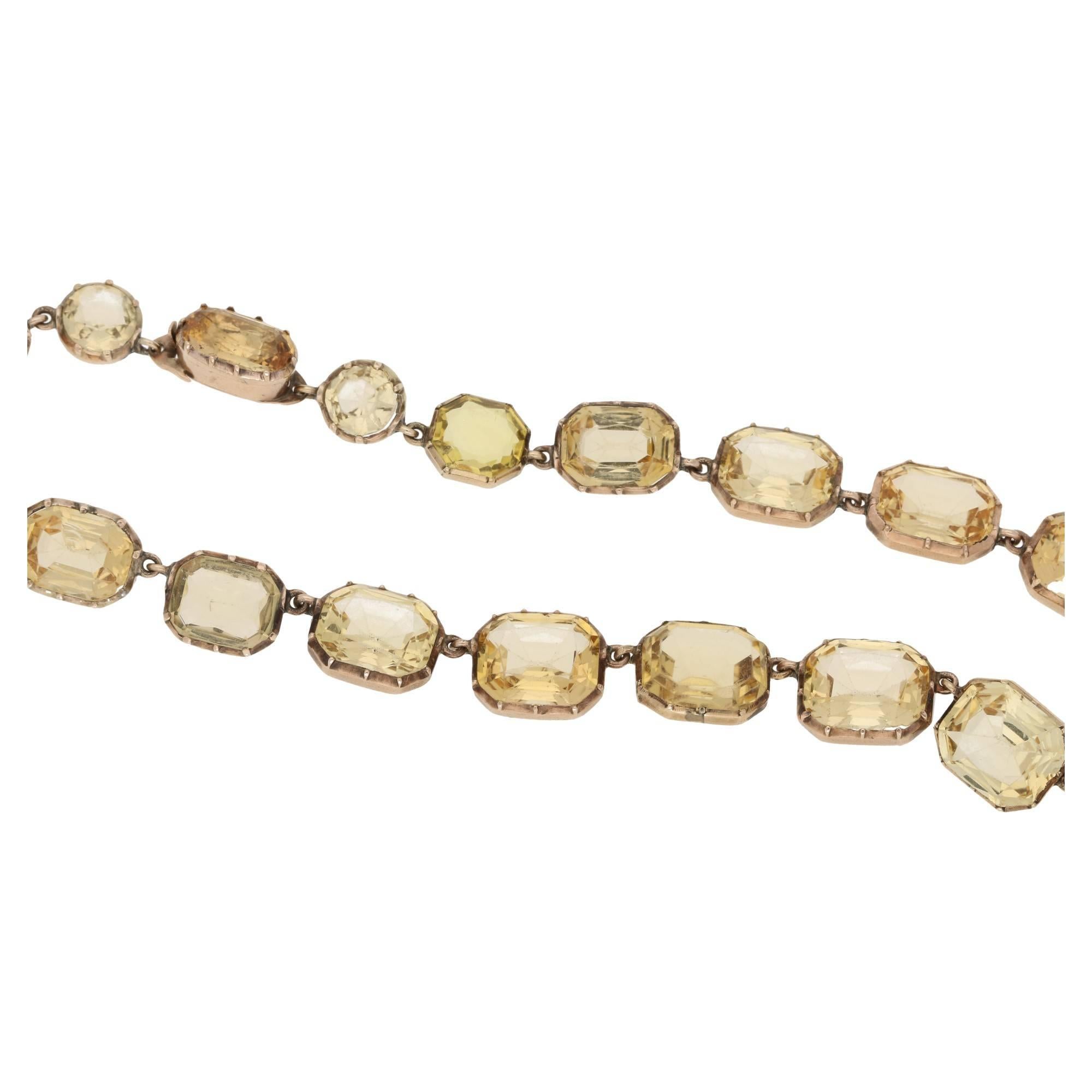 An important Victorian Imperial topaz riviere necklace set in  yellow gold. Comprising of long oval topaz hiding a tongue in groove clasp, shouldered by a pair of round faceted topaz's and completed with twenty five graduated rectangular scissor cut