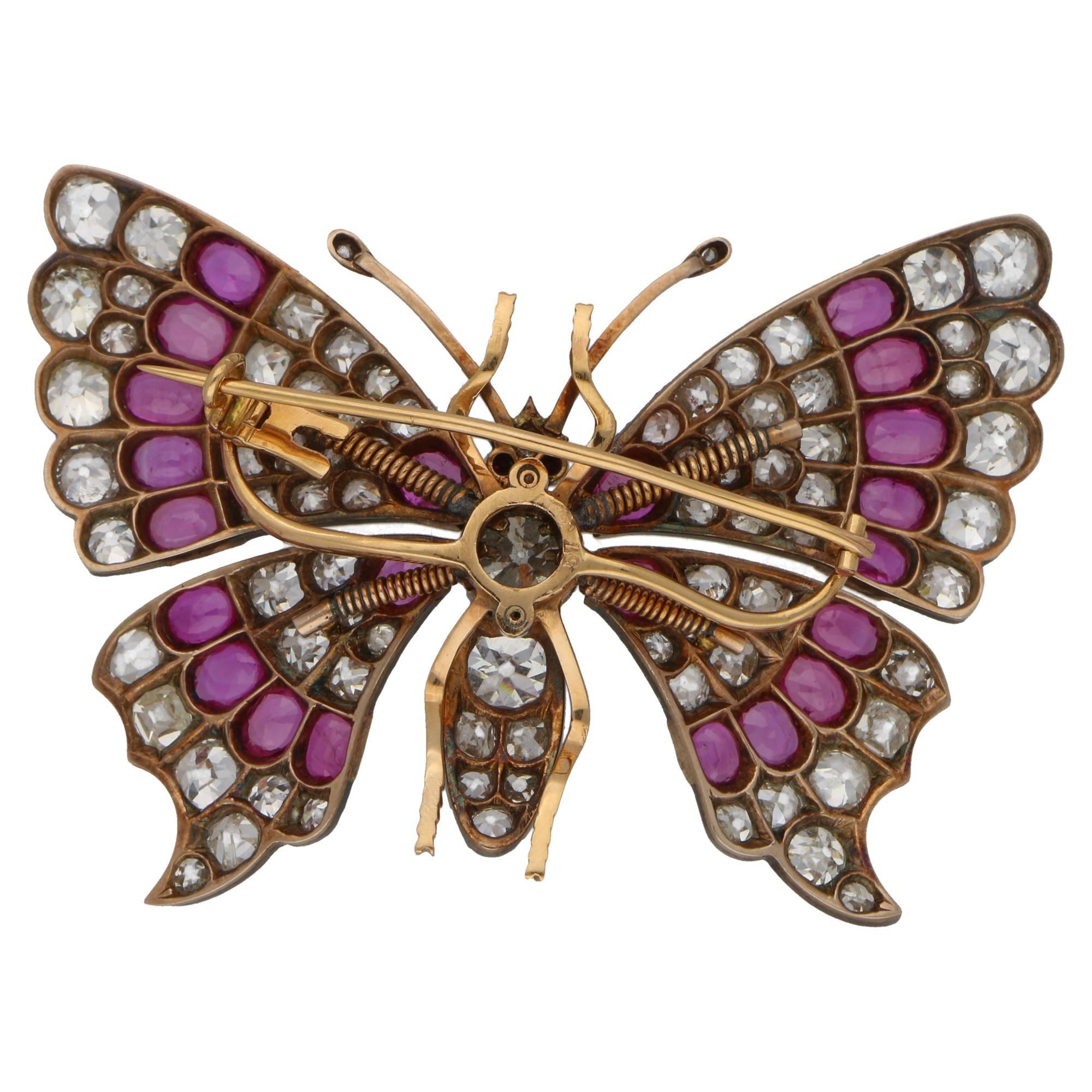 A stunning butterfly brooch set in 18ct rose gold and silver, featuring sprung set fluttering wings grain set with diamonds and rubies. The body of the butterfly is grain set with diamonds, featuring one large 1.44ct Old European cut diamond in the