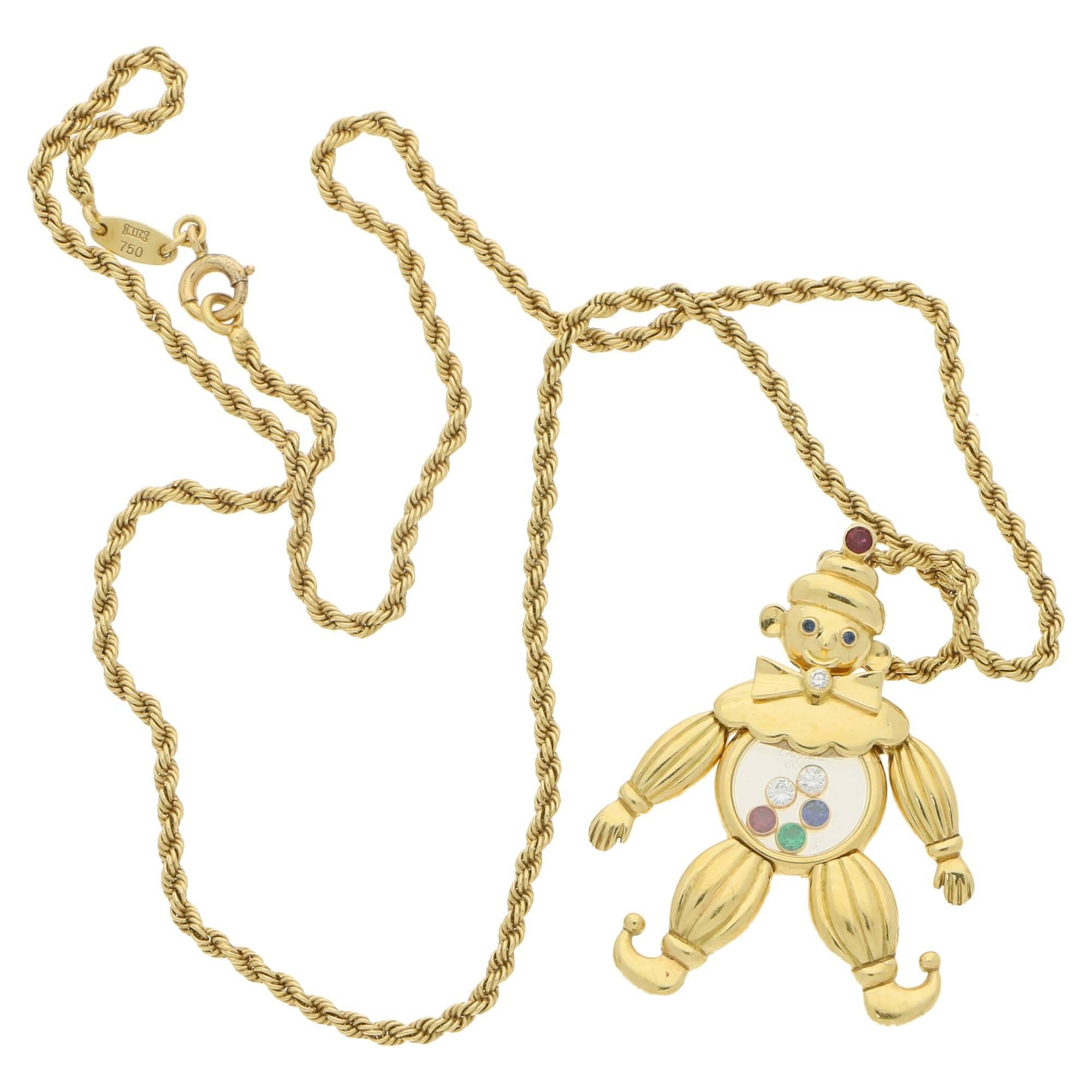 A whimsical articulated Chopard clown pendant set in 18ct yellow gold. With moving legs, arms, head and bow tie. The colourless sapphire crystal body encases two floating diamonds, a ruby, a sapphire and an emerald collet set in 18ct yellow gold.