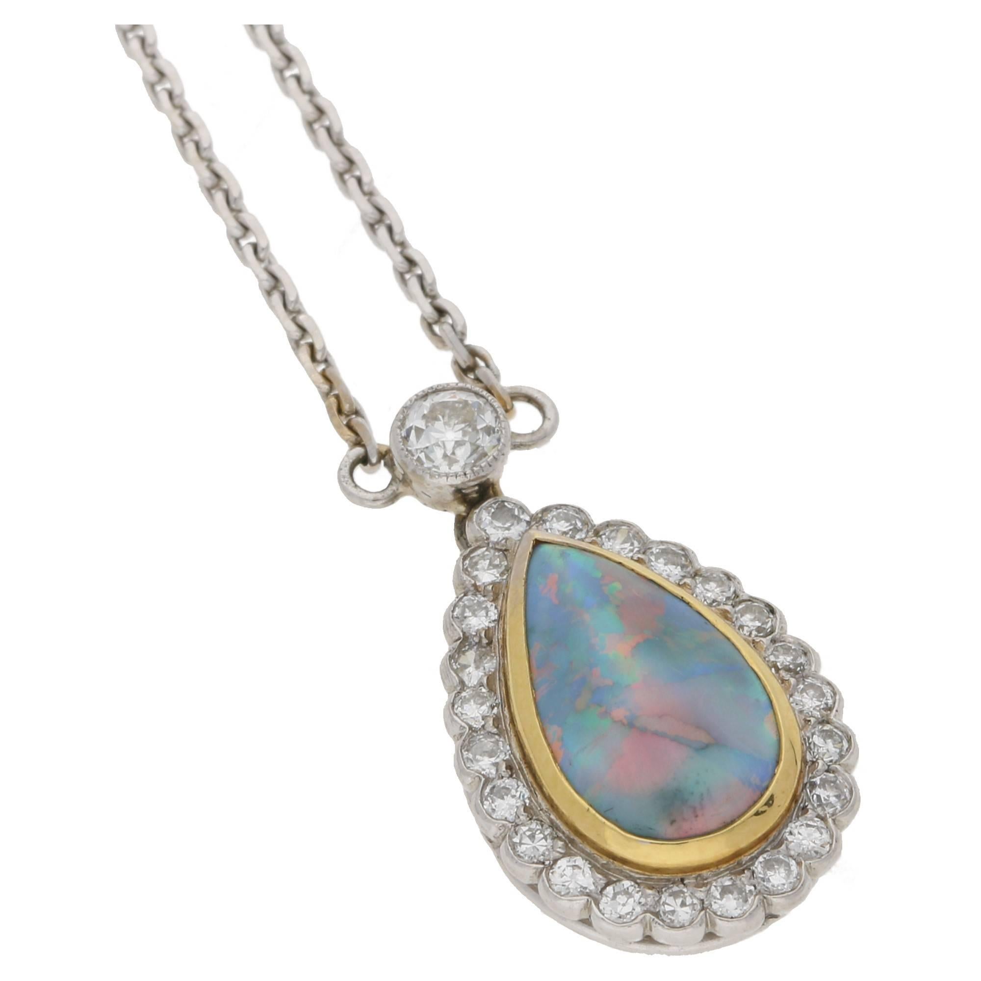 An opal and diamond cluster pendant. The pendant is formed of one tear drop black opal, rub-over set to the centre in yellow gold with twenty three Old European cut diamonds in a millegrain setting forming the outer detail. The pendant is suspended