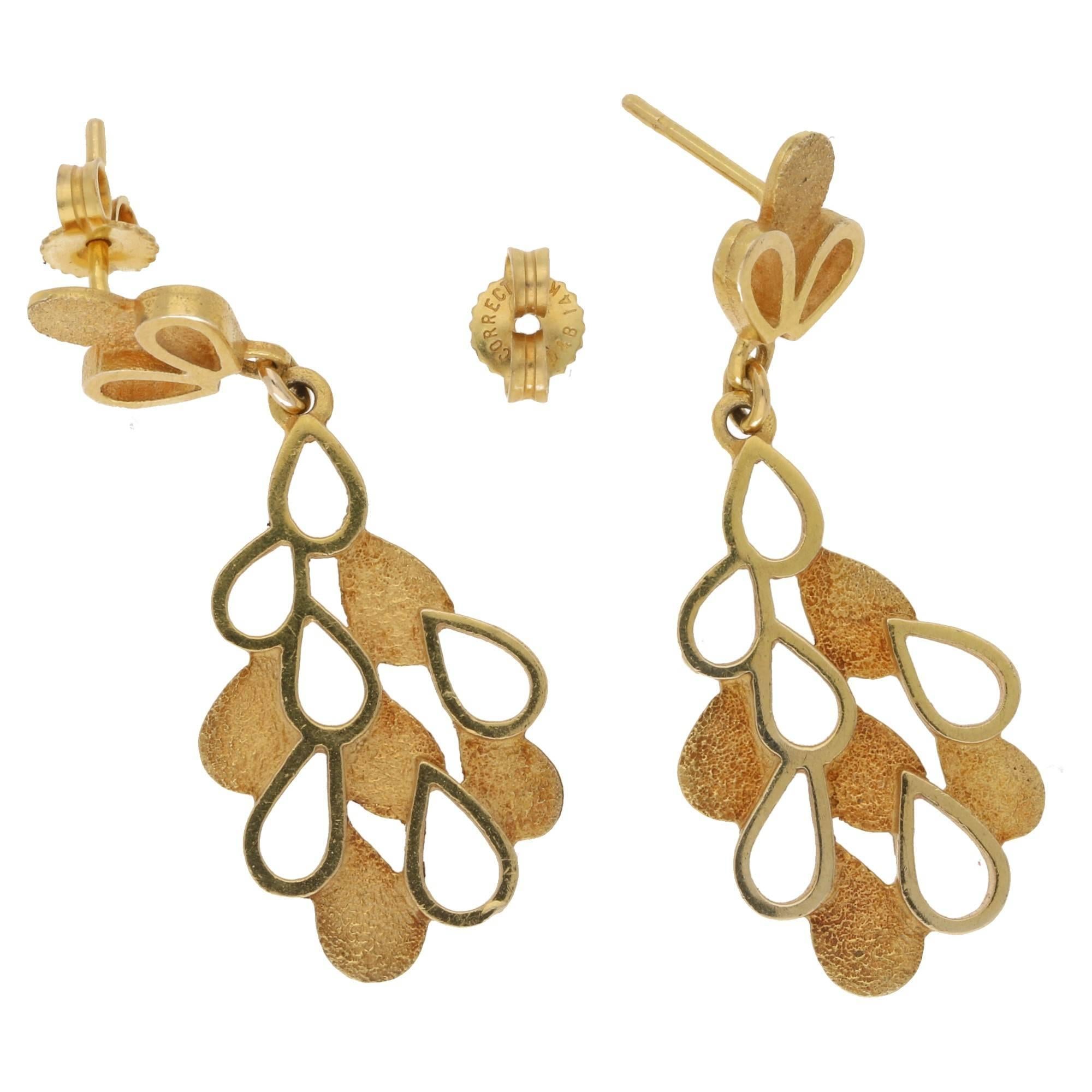 A fanciful pair of 18ct yellow gold textured raindrop cut out earrings. Each comprising of a hanging section with full textured rain drops and empty raindrop cutouts, suspended from a terminal with raindrop like detailing, the centres are textured