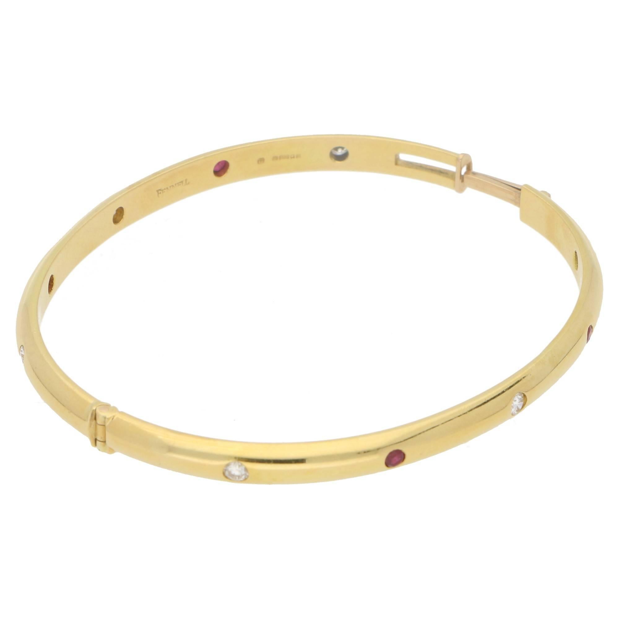 A stunning 18ct yellow gold Theo Fennell ruby and diamond set hinged bangle. With six round brilliant cut diamonds and four round faceted rubies drop set alternating into the bangle. Estimated total ruby weight: 0.50cts. Estimated total diamond