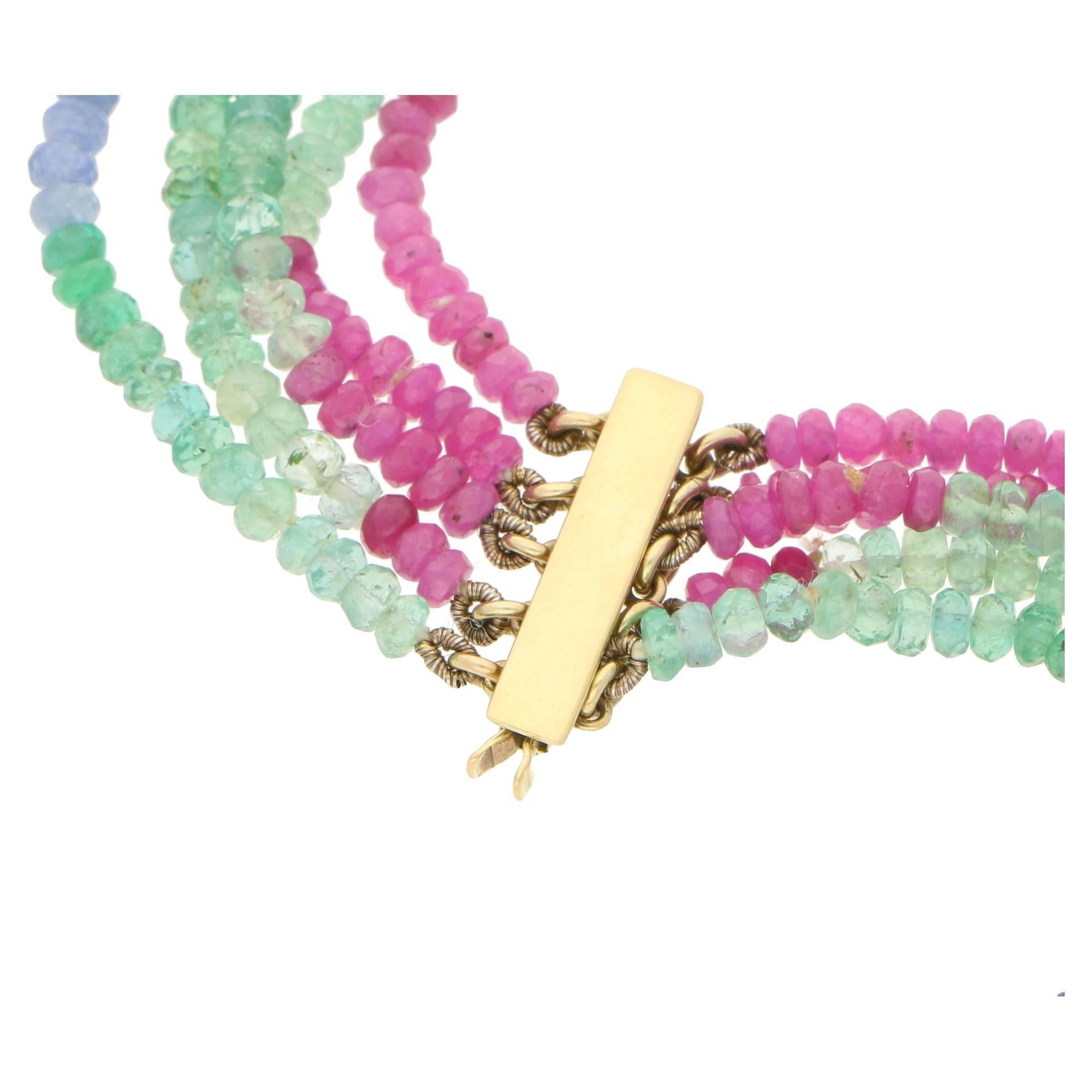 A vibrant and colourful fitted five row sapphire, ruby and emerald briolette bead necklace. Leading to a five row bar clasp in 9ct yellow gold. Estimated total gem weight: 346cts. Measuring 20 inches in length.