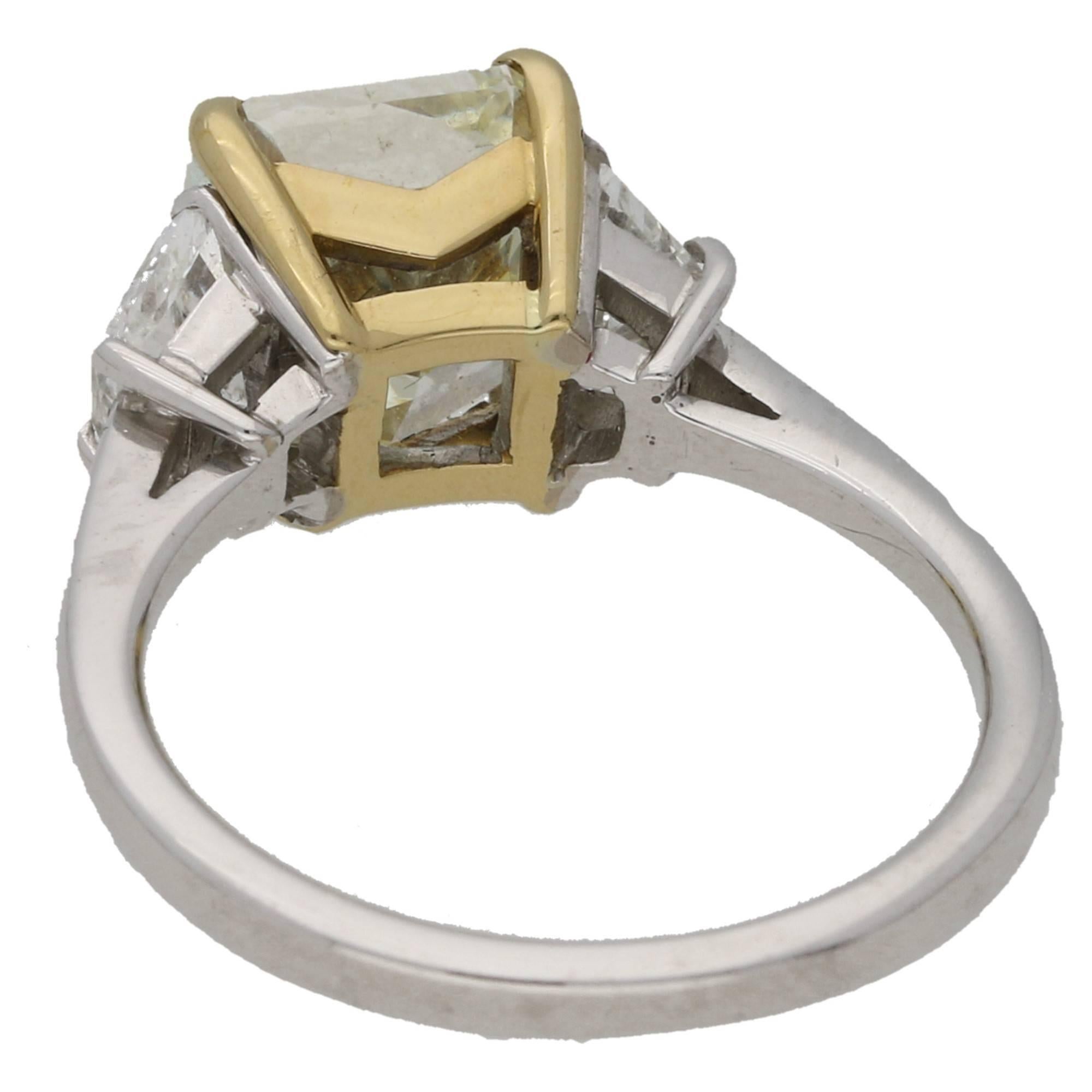 A simply stunning three stone yellow diamond engagement ring set in 18k yellow and white gold. The piece is centrally set with a natural fancy yellow radiant cut diamond which is independently certified as 3.51 carats, VS clarity. This is set in a