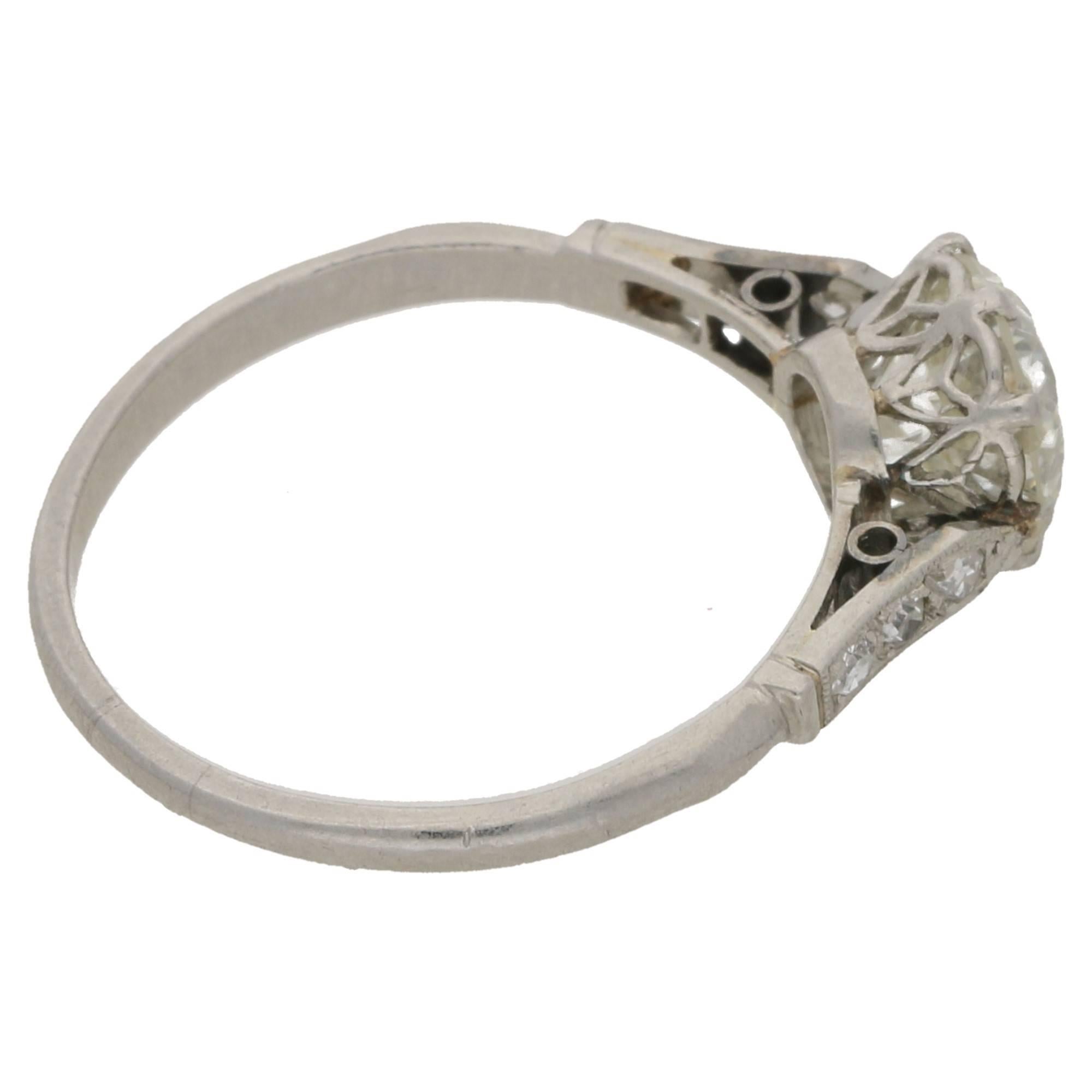 A delightful Edwardian platinum ring set with an Old European cut diamond. The diamond is eight-claw set in platinum and has pinched shoulders channel and grain set, with eight cut diamonds. The ring has an exquisite Gothic style pierced openwork