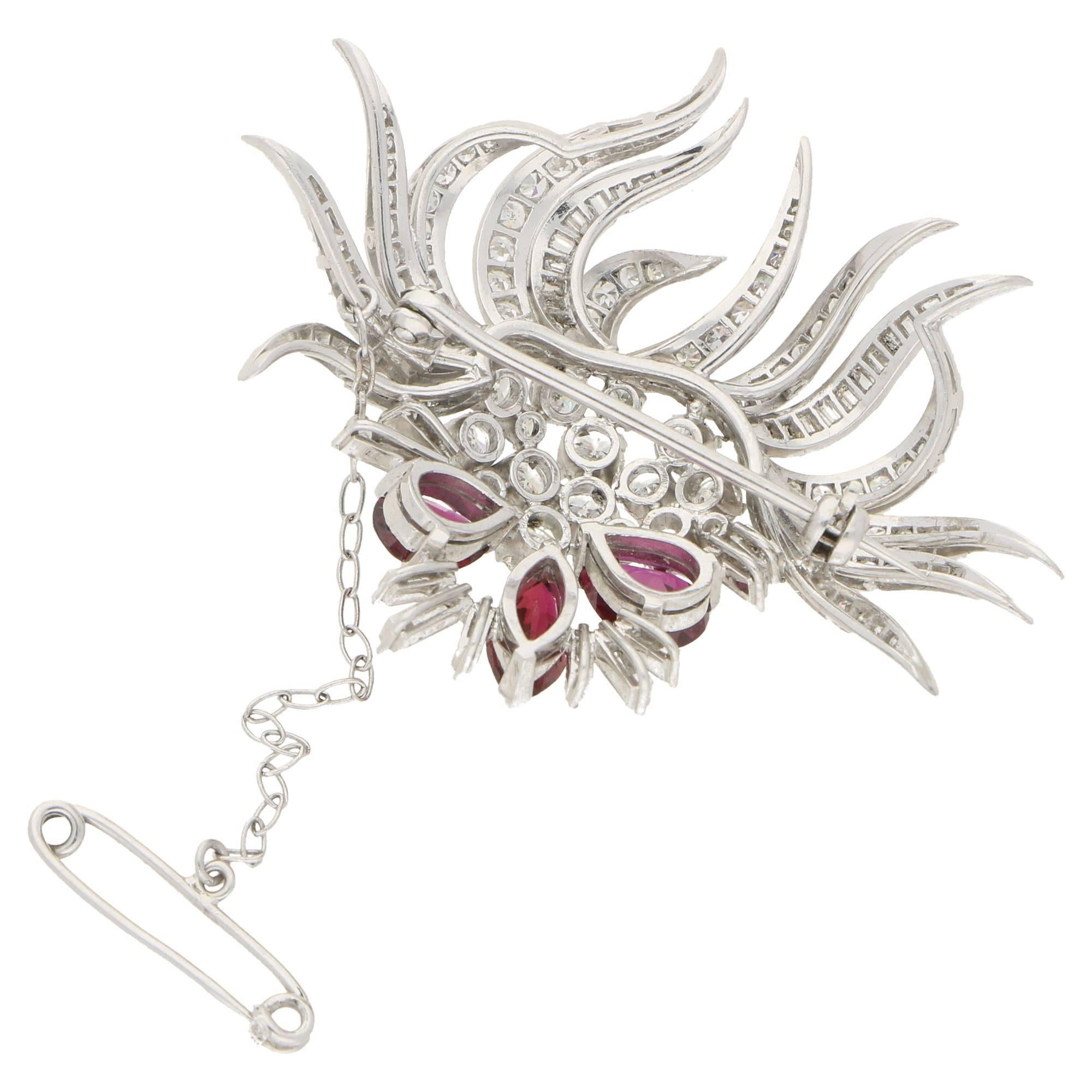 A fantastic ruby and diamond brooch set in platinum featuring two pear and one marquise shaped faceted rubies in claw settings and beautiful sunburst of mixed cut diamonds, consisiting of well-matched round brilliant cut, baguette cut and calibre