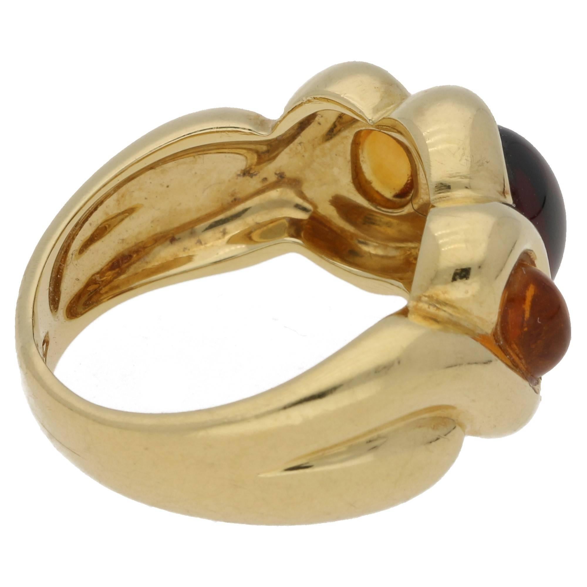 A chunky great fun ring, in hallmarked 750 (18 karat) gold. Set with two citrine cabochon cut stones, flanking a central garnet. Ring size is presently a UK N, but this can be sized upon request.