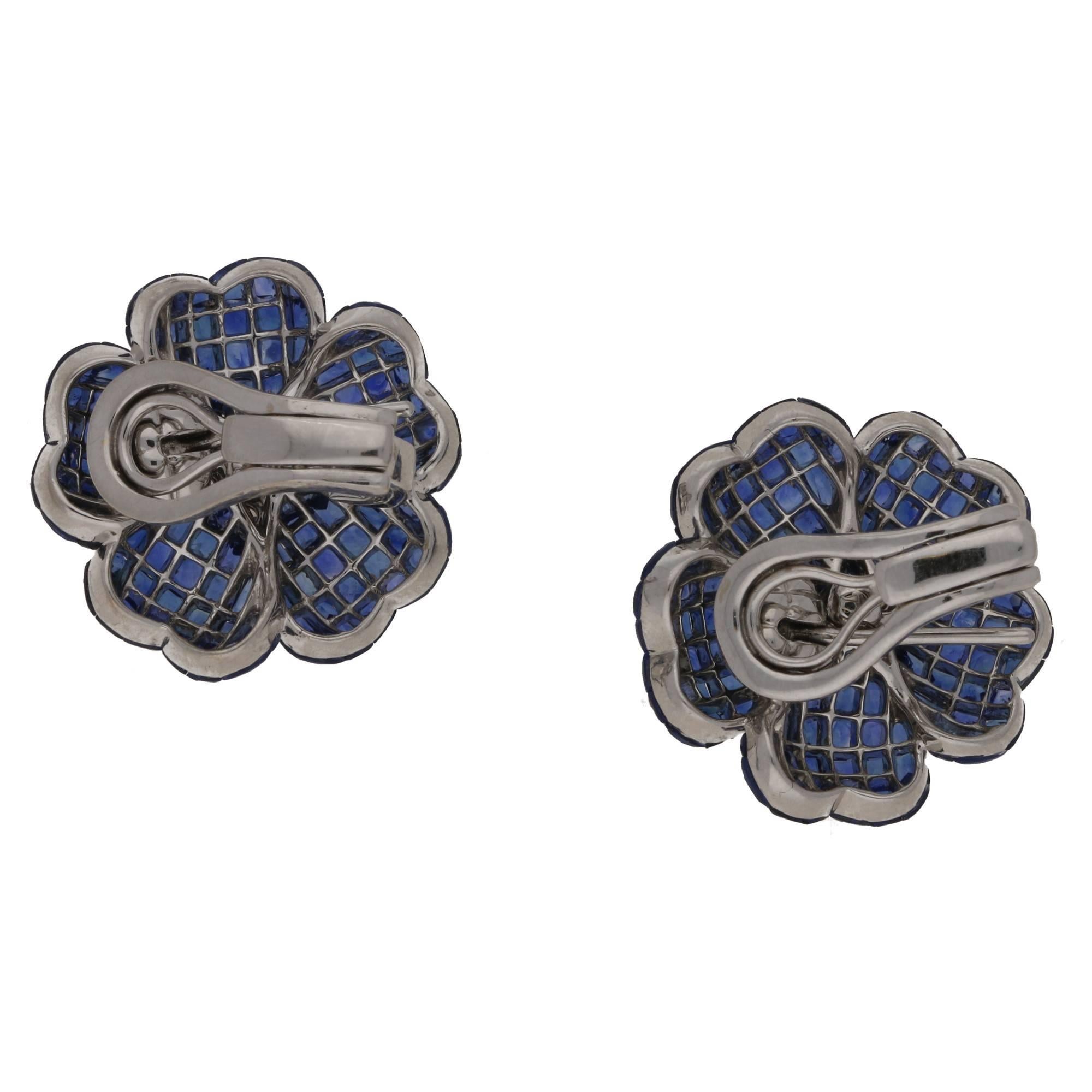 An exquisite pair of invisibly set sapphire and diamond flower earrings. With calibre cut sapphires adorning the softly undulating petals, centered with round brilliant cut diamonds claw set. Set with fold-able post and sprung clip fittings.
