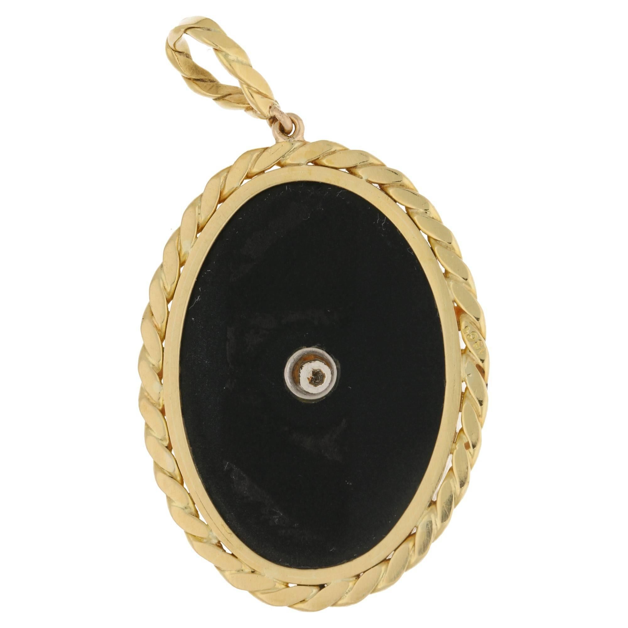 An onyx and diamond set pendant in 18ct yellow gold. With a round brilliant cut diamond centrally set in an 18ct white gold collet in an oval onyx panel encased in a border of 18ct yellow gold closed curb linkwork. Estimated diamond weight: 0.70cts.