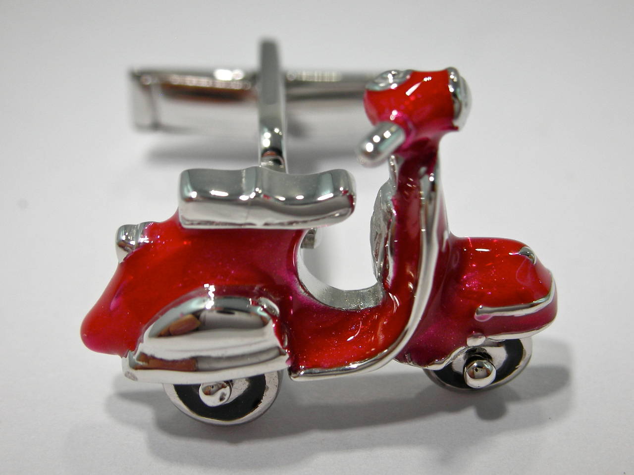 Jona enameled sterling silver scooter cufflinks with rotating wheels; are available in six different colors or plane rhodium plated.
Dimensions: H 1.66 in x W 0.90 in x D 0.20 in - H 23.05 mm x W 23.05 mm X D 5.17 mm.
All Jona jewelry is new and has
