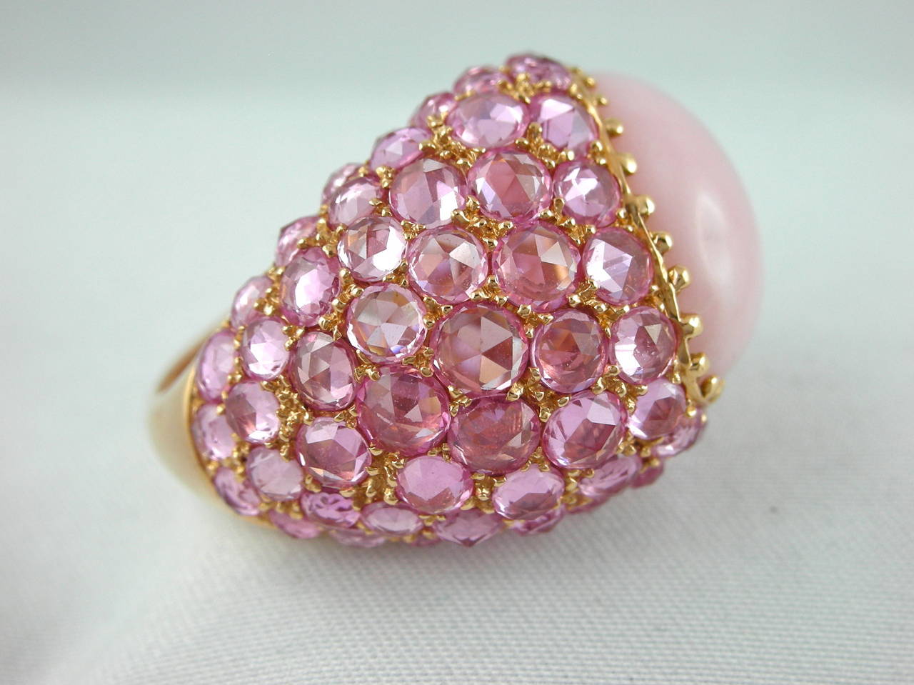 A dome ring by Jona, featuring 7.52 carats of pink rose-cut sapphires with a 10.33 carats cabochon pink opal set in 18 karat rose gold, hand crafted in Italy.
US size: 6.5 (can be sized)

All of our jewelry is new and has never been previously