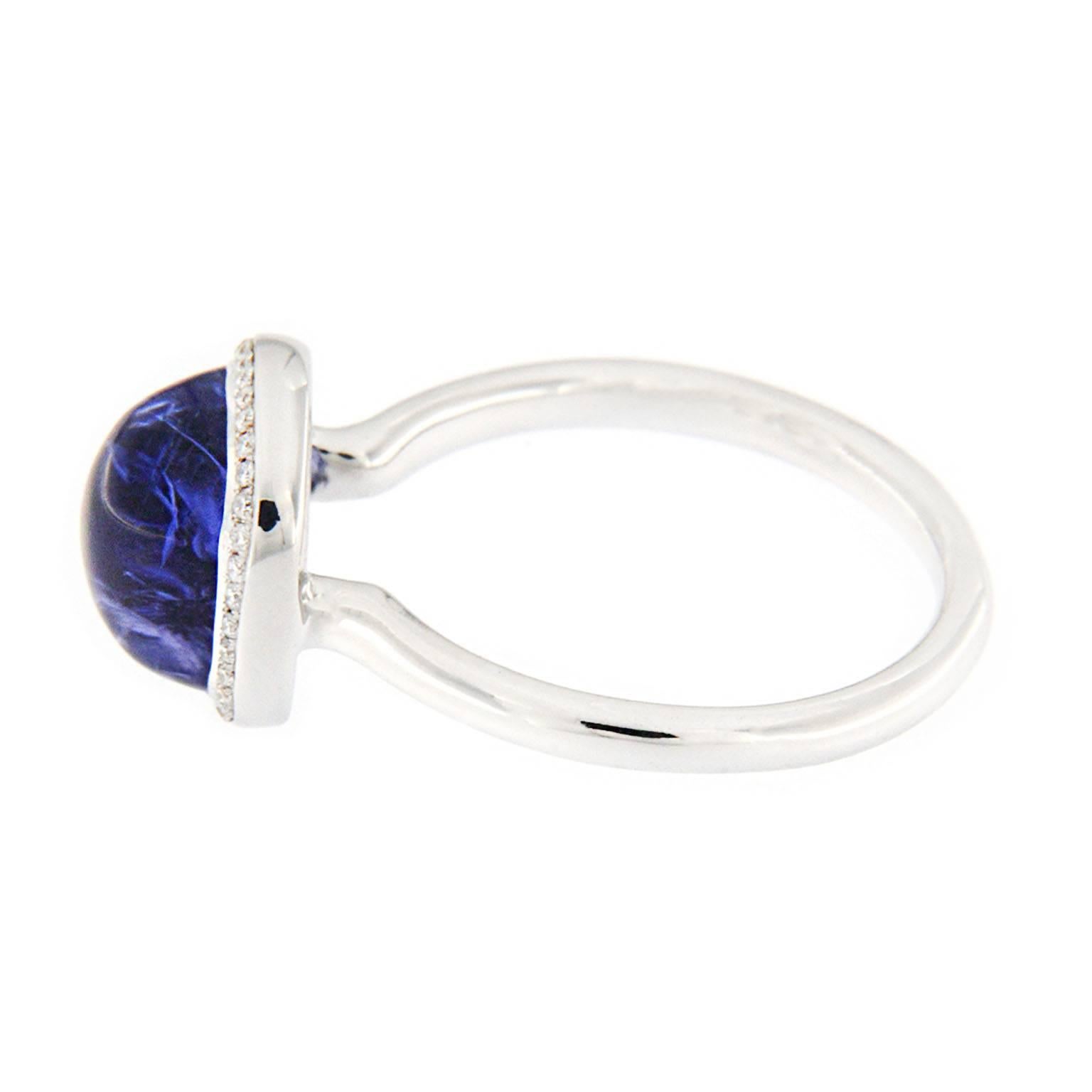 Jona design collection, hand crafted in Italy, 18 karat white gold ring centering a cabochon Tanzanite weighing 4.8carats, surrounded by a row of round-cut diamonds weighing  0.09 carats (G-color/ VVS1-clarity). Ring size US. 6 1/4, can be sized to