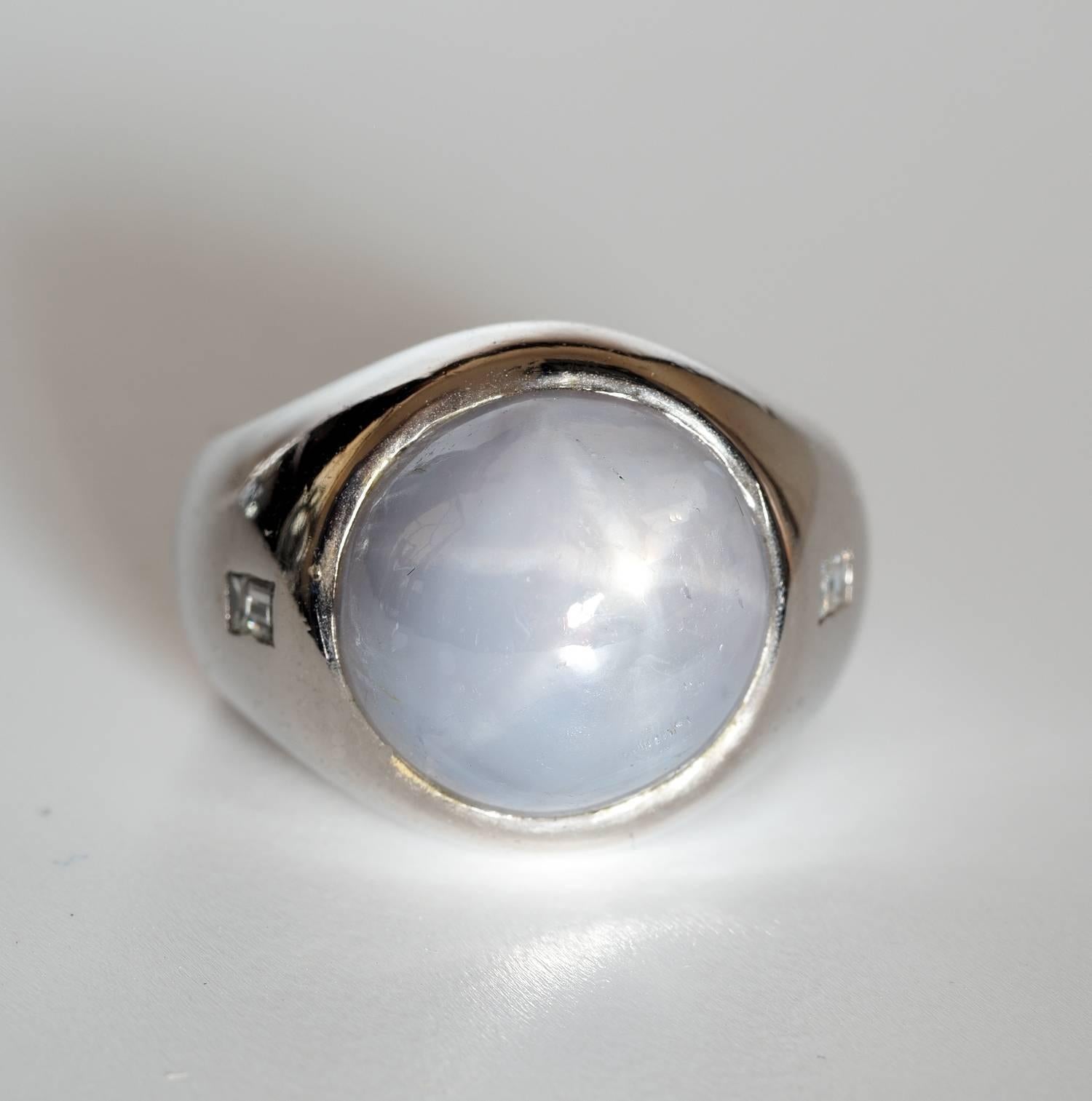 Fabulous design, massively constructed od solid 18 KT white gold
Set with a large Natural no heat Star Sapphire of light grey with six pointed star phenomena
13.40 Ct estimate on mounting
Sleek elegant mount enriched with two little rectangular cut