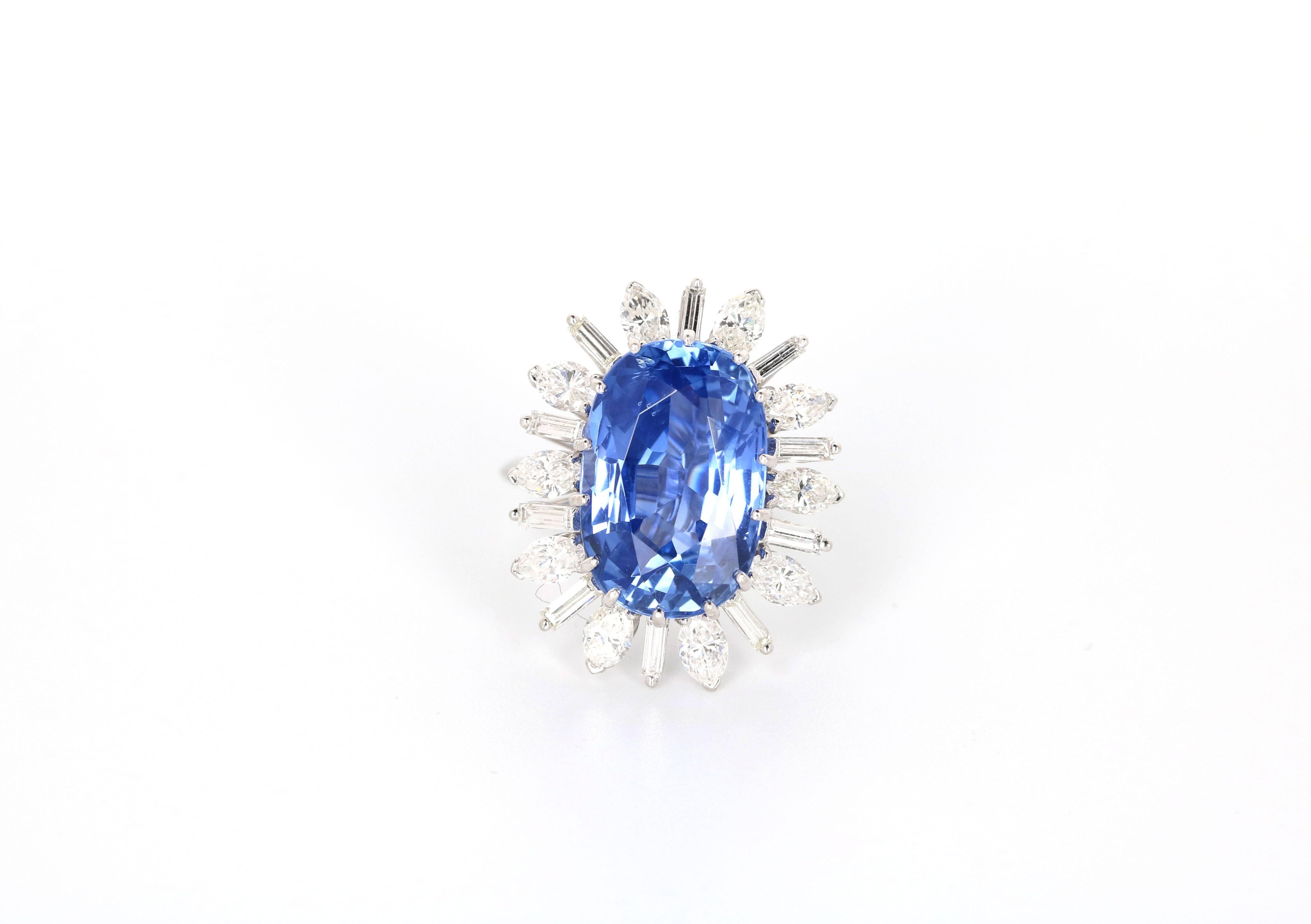 A very elegant ring with a unheated blue oval scissor step cut Ceylon sapphire of 13.20 carats. Surrounded by 10 navette shape diamonds weighing approximately 1.50 carats and 10 tapered baguette diamonds weighing approximately 0.50 carats in a 18K