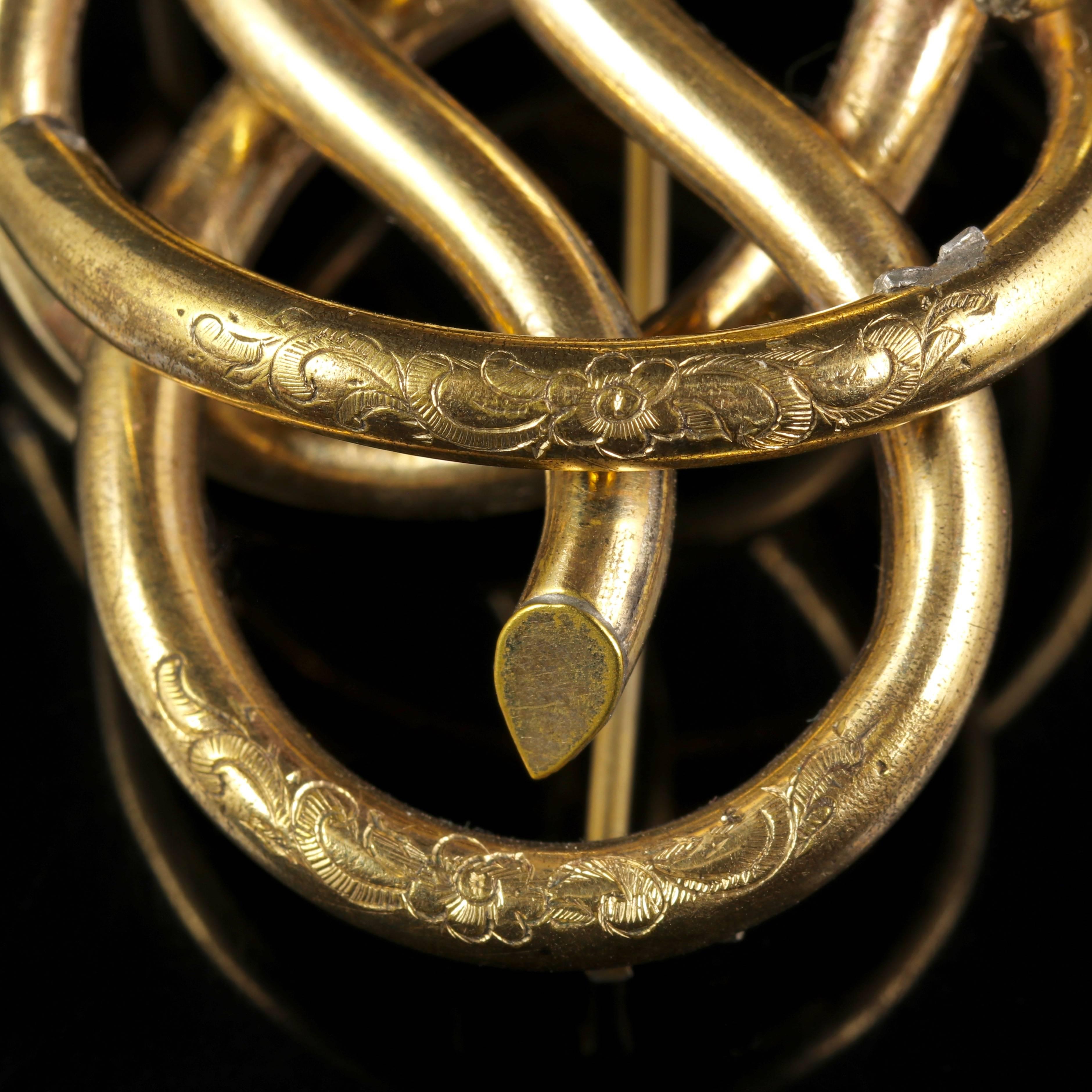This fabulous Victorian Knot brooch is Circa 1880.

The Brooch boasts stunning workmanship throughout and has a beautiful twisting rope design. 

Set in Base Metal with a smooth Gold finish.

Complete with a beautiful engraved outer gallery which
