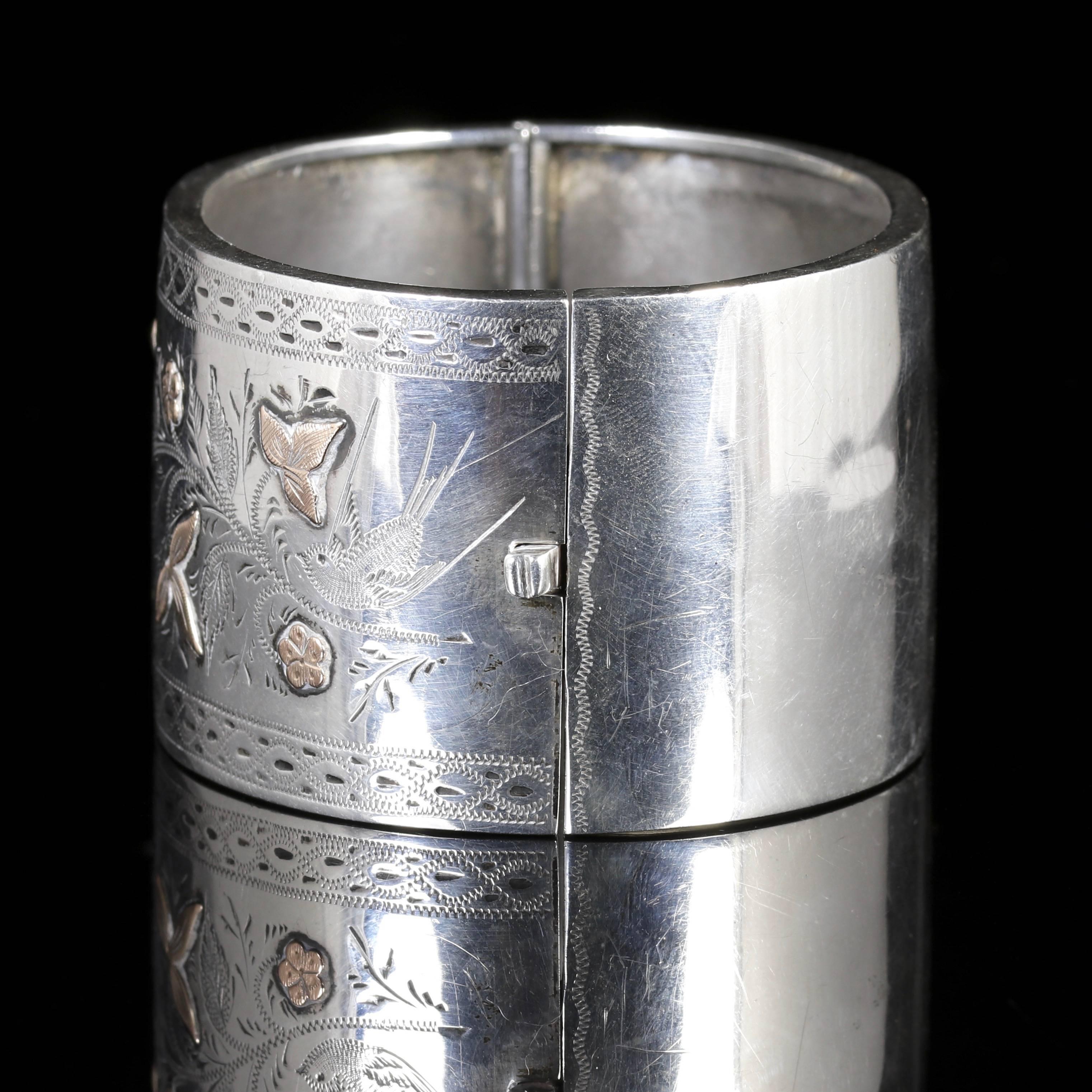 This fabulous Victorian Sterling Silver and Gold  bangle is exceptional.

The beautiful bangle depicts a butterfly and bird in flight among foliate motifs in Silver and Gold.

Forget me nots and Ivy can be seen upon the face of the bangle.
