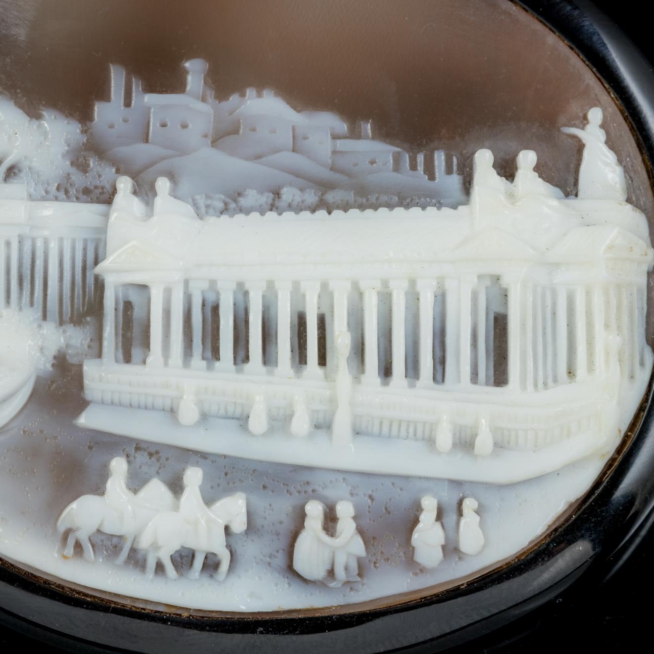 This wonderful antique Whitby Jet Cameo brooch is Victorian, Circa 1860.

The lovely hand carved Cameo depicts a lovely city scene which we believe could be Edinburgh in the Victorian era, with the spectacular National gallery in front and the