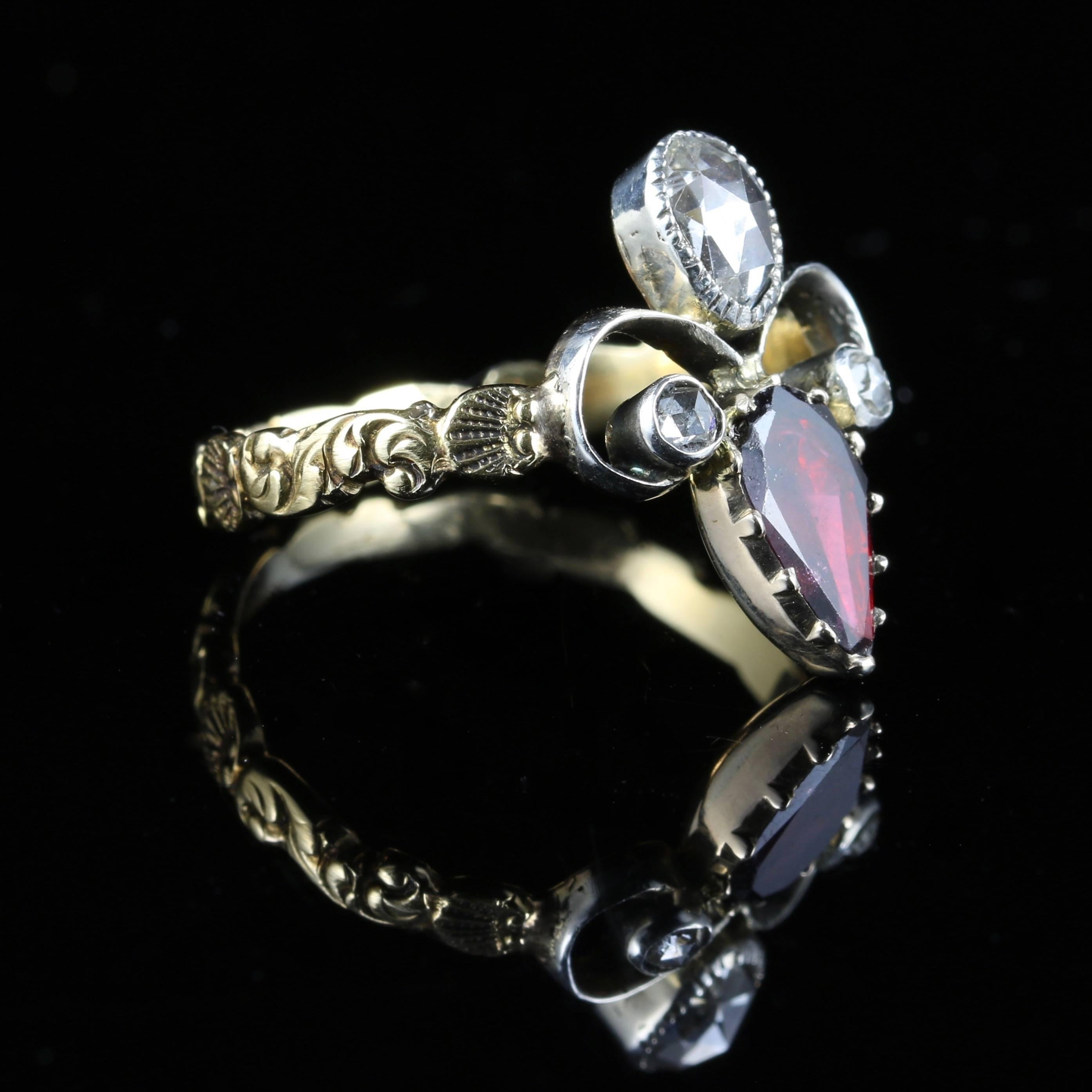 This fabulous Fleur De Lis ring is set with a lovely deep red Garnet and three beautiful Rose Cut Diamonds. The top Diamond spreads 0.65ct approx. 

A beautiful ornate 18ct gold shank is set with lovely interlinking flowers. 

The fleur-de-lis is a
