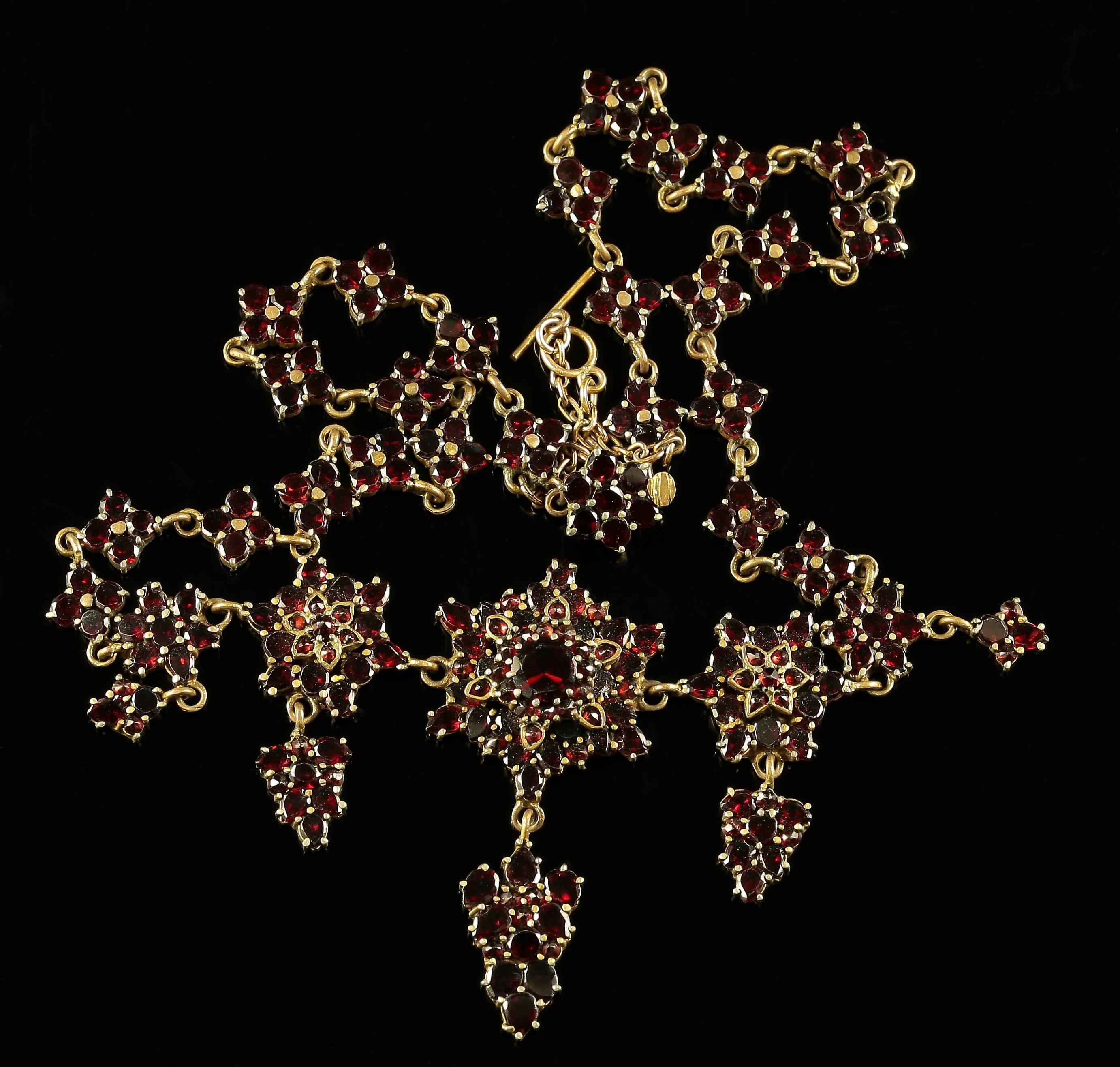 This fabulous Antique Victorian Garland Garnet necklace is all genuine set in garnet gold. 

Circa 1880

The garnets are beautifully set leading to a large central section 

The necklace is adorned with five pendants that cascade from this