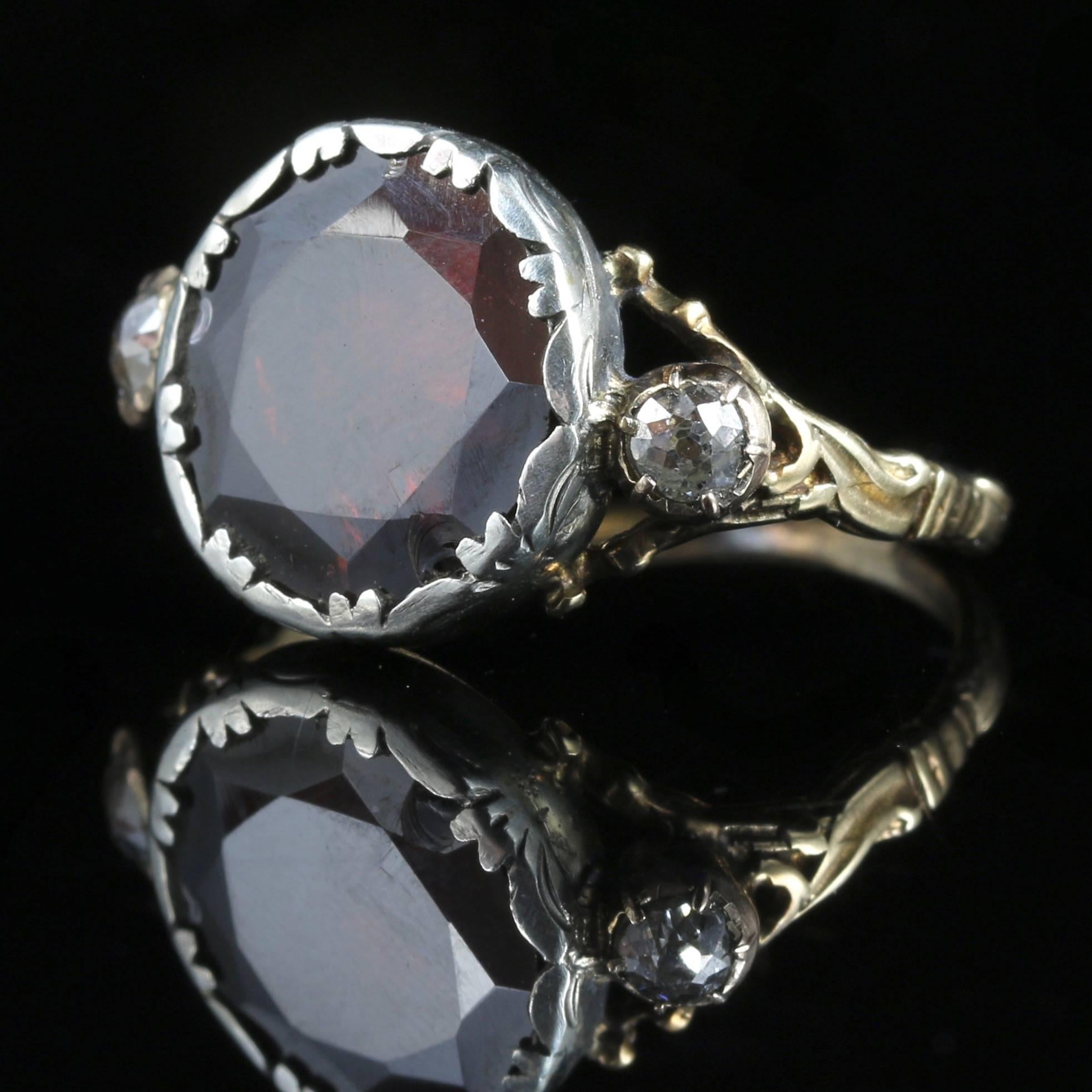 This is an amazing ring, a wonderful 5ct flat top Garnet sits proud of its gallery flanked with a diamond on each shoulder. 

The flat topped garnet is set in silver, the diamonds are set in 18ct yellow gold. 

The Garnet is a stone of purity and