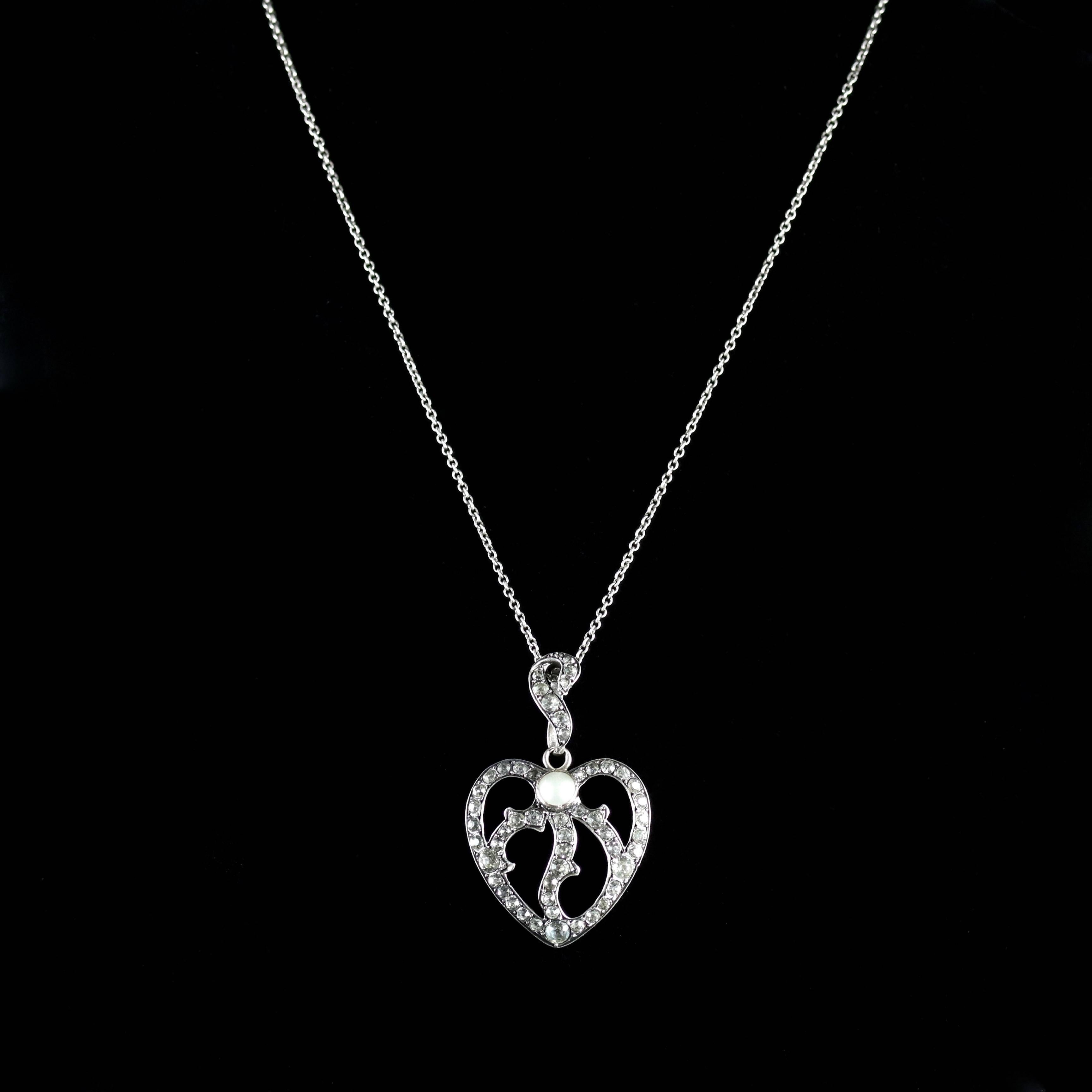 This beautiful Sterling Silver Victorian heart is set with lovely White Paste Stones which adorns this beautiful heart and central Pearl.

Beautiful Paste Stones are also set into the decorative bale.

Paste is a heavy, very transparent flint glass