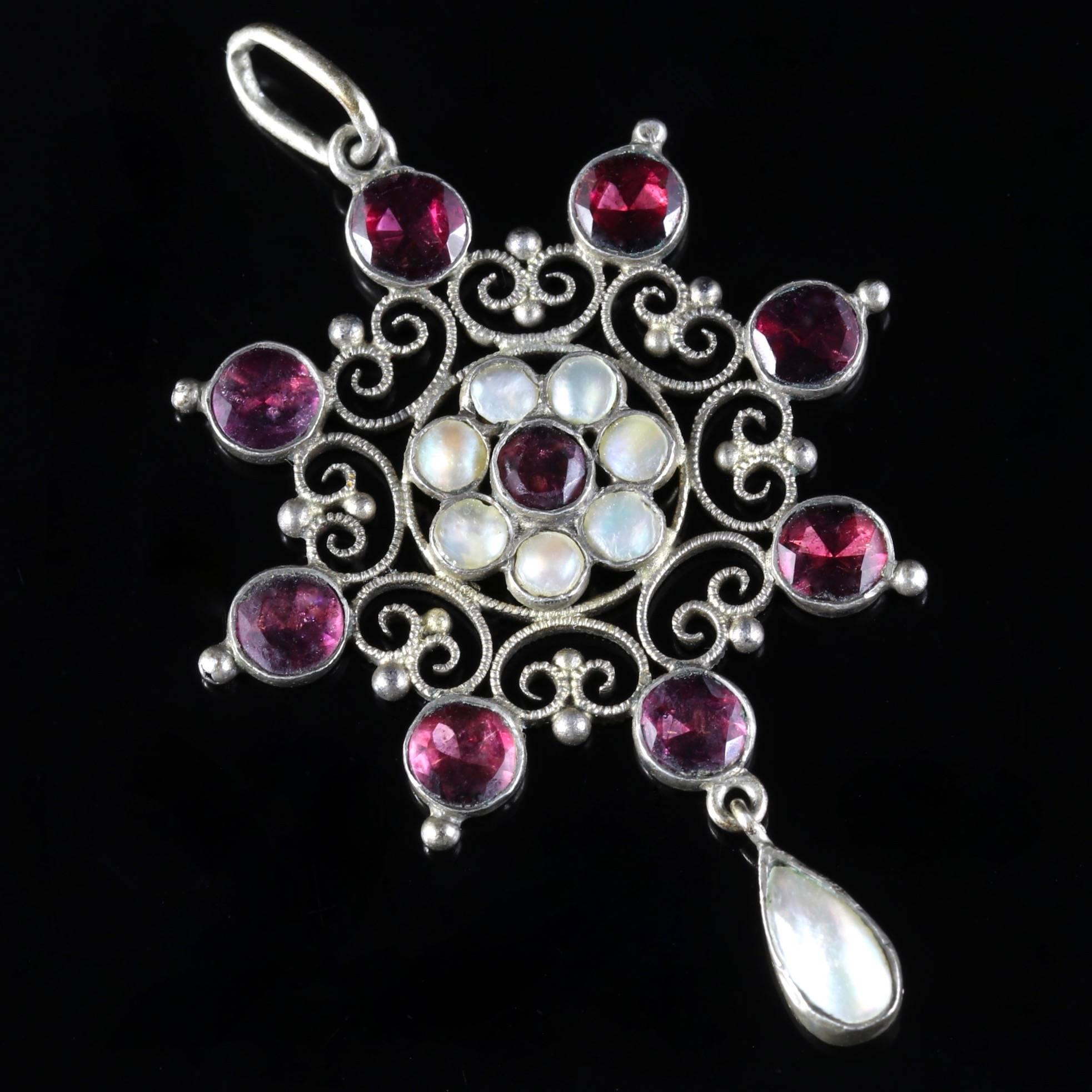 This fabulous Arts and Crafts Flat Top Garnet and Blister Pearl pendant is modelled in Silver and Metal, Circa 1900. 

The lovely pendant is adorned with 8 deep, red Garnets which surround a charming flower which has 7 Blister Pearls nested inside
