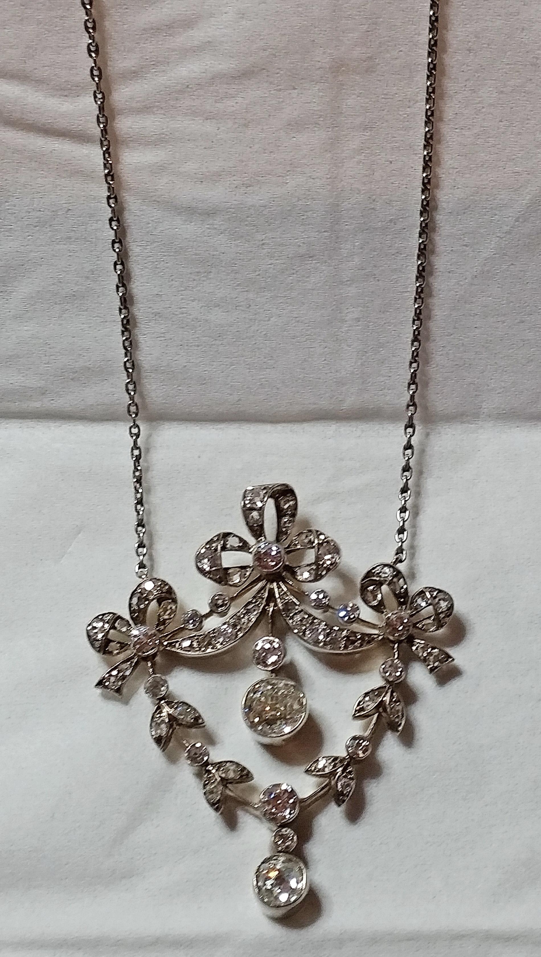 Golden Art Nouveau necklace of most elegant appearance,  looking like stylized flower's blossoms attached to leafy stems - these ones hung up at bows / meshes visible at top area.

Covered with various diamonds (vintage cuts), having 3.0 carat in